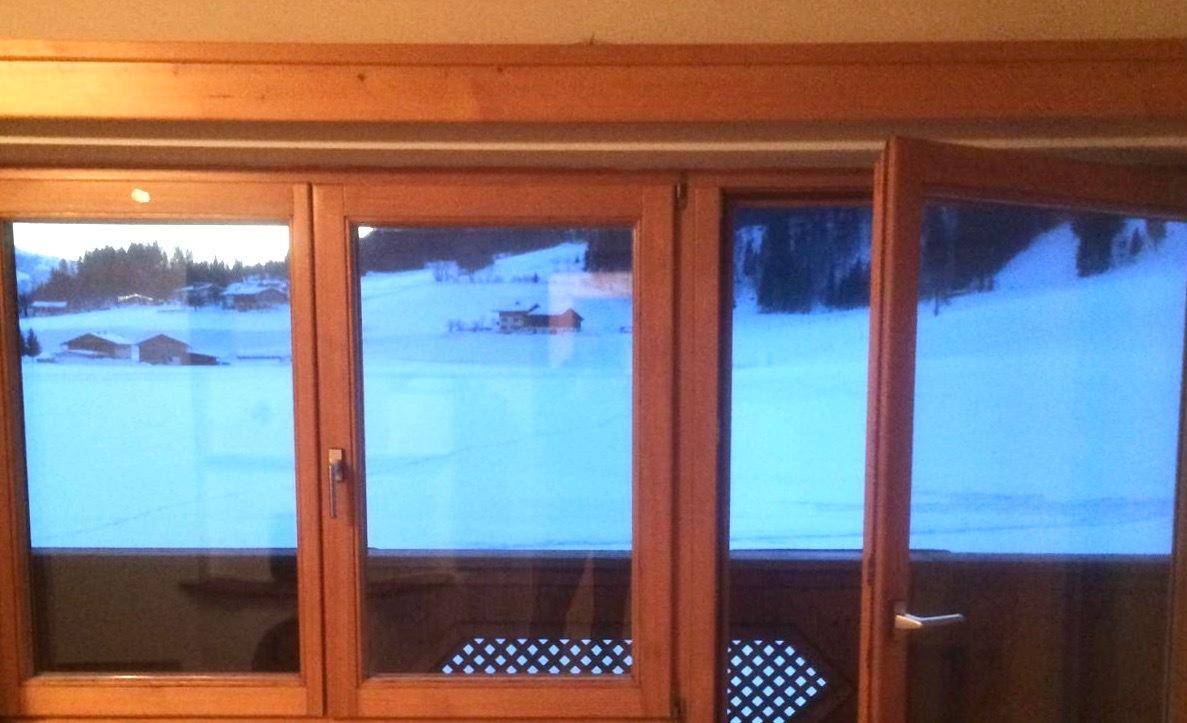 Blick aus dem Fenster auf eine verschneite Winterlandschaft mit Häusern in der Ferne.