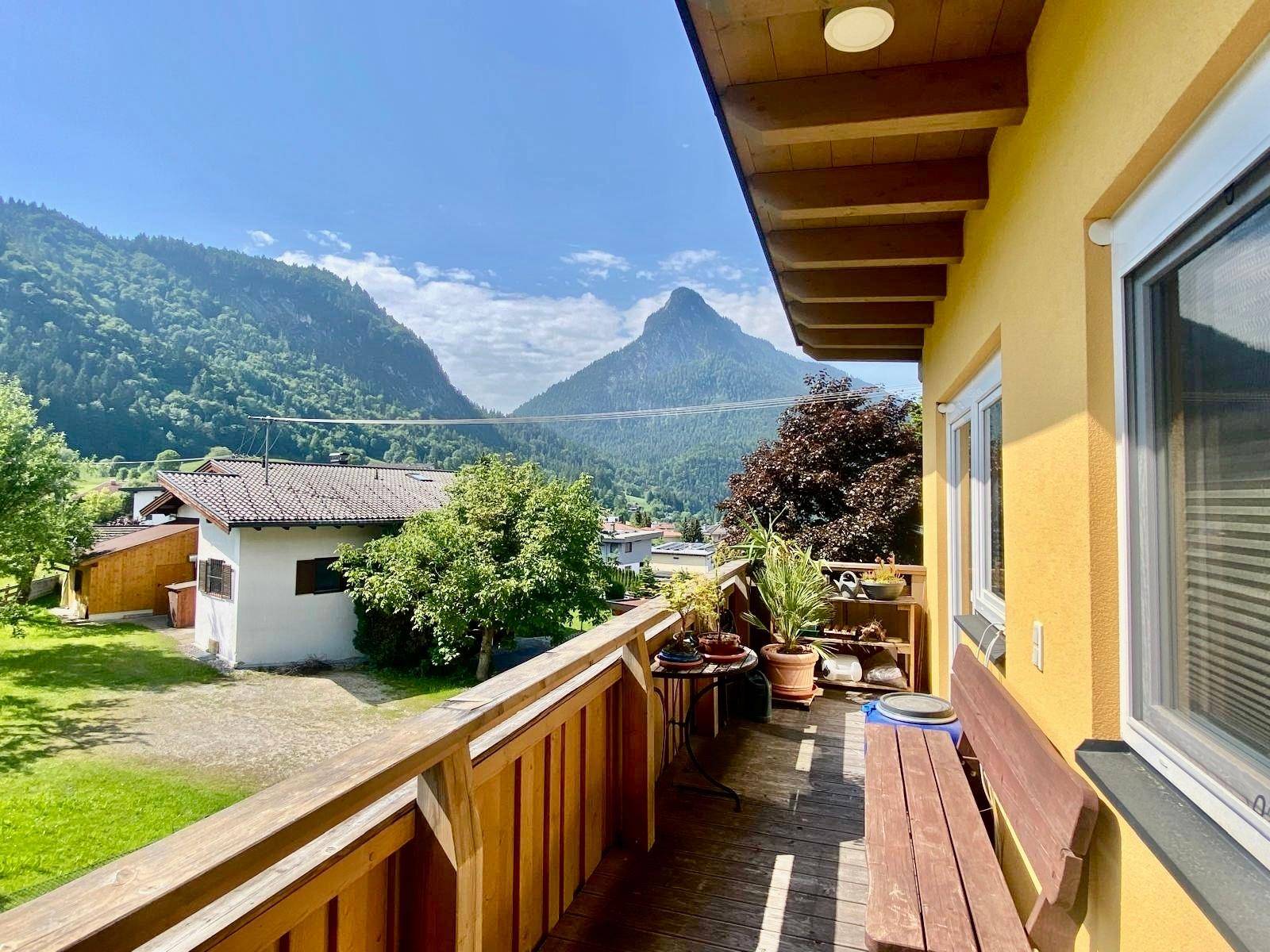 Geräumiger Holzbalkon mit Sitzbank und weitem Blick auf die Berge und das Tal.