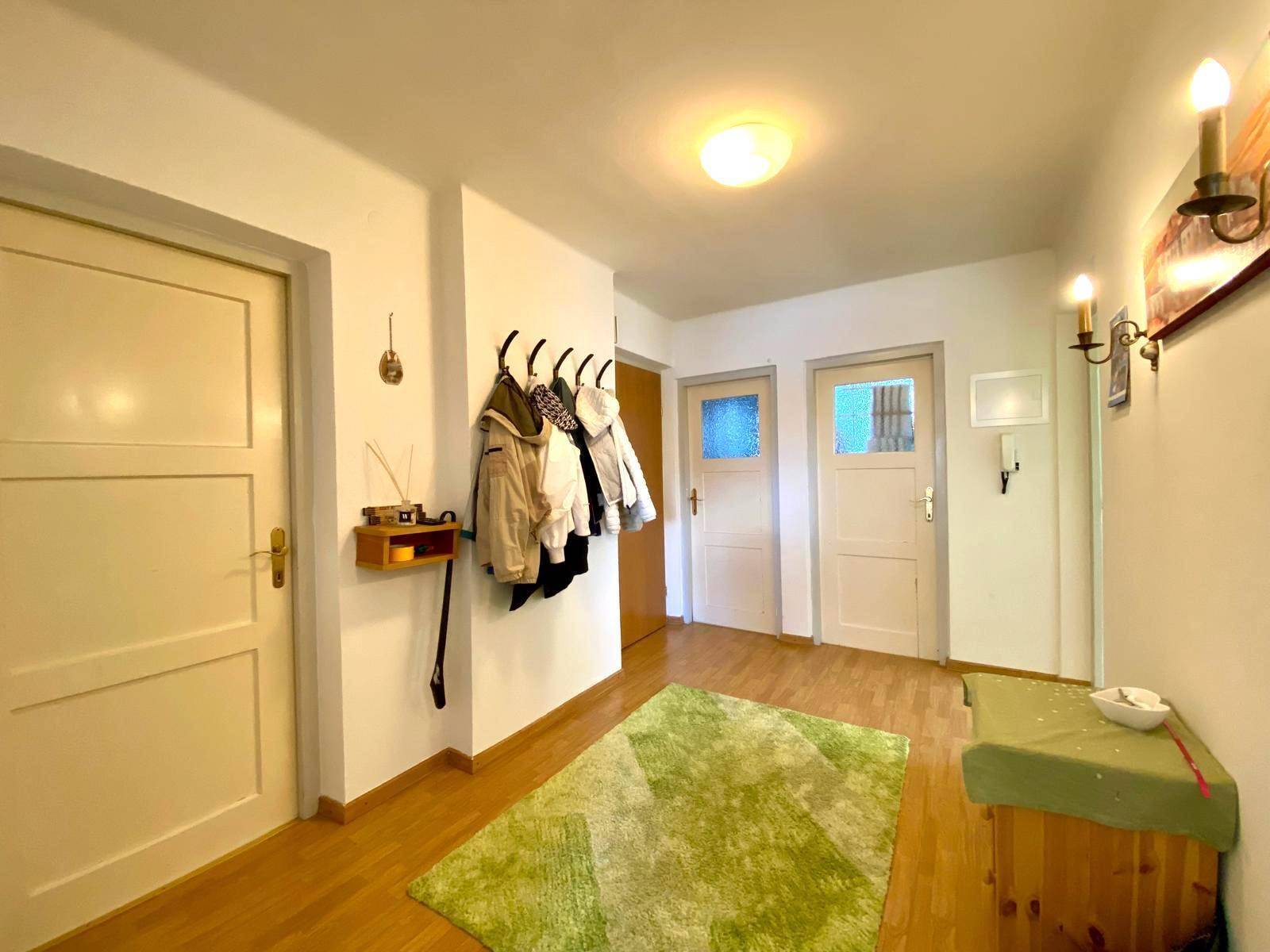 Heller Flur mit Garderobe, Holzboden und mehreren Türen zu den Zimmern.