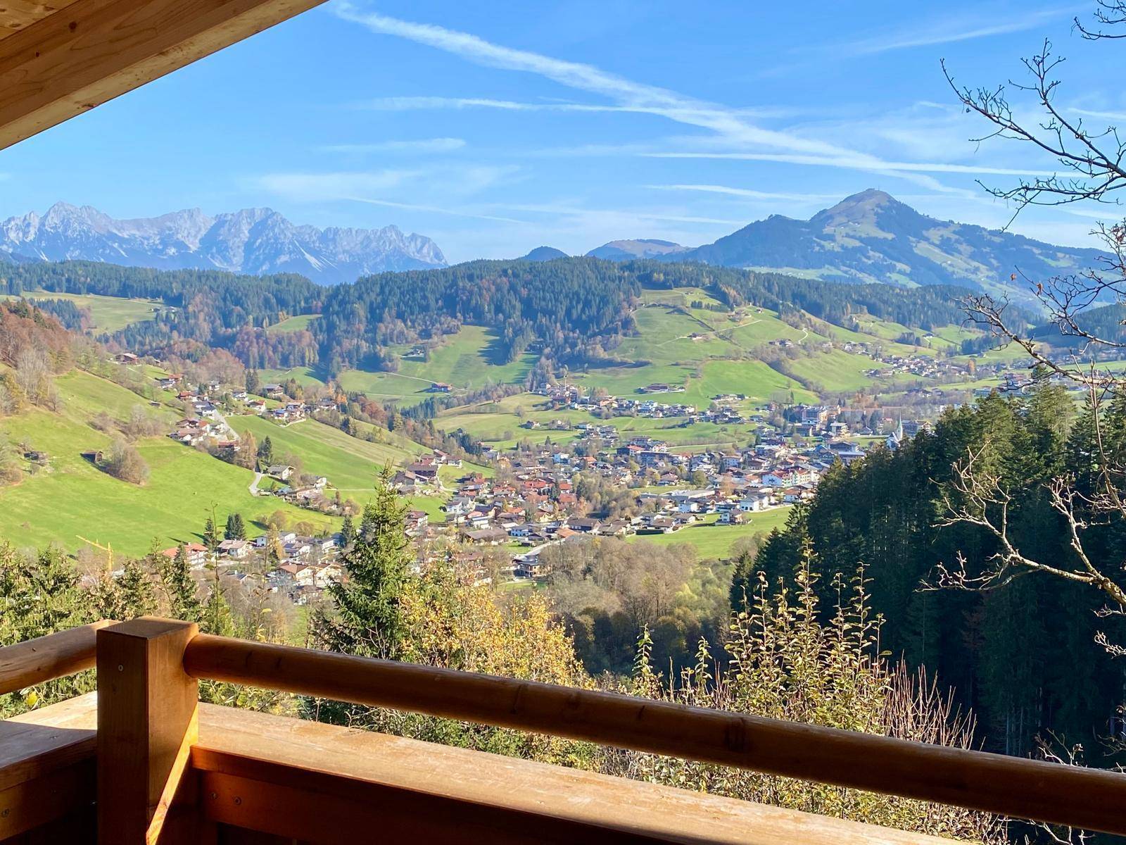Panoramablick vom Balkon über das grüne Tal und die umliegenden Berge unter blauem Himmel.