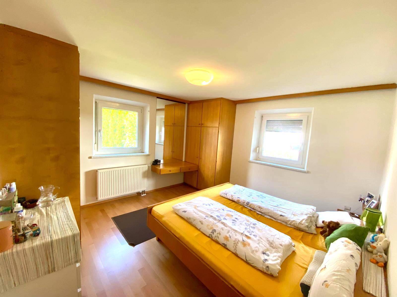 Schlafzimmer mit zwei Einzelbetten, Holzschrank und Fenster mit Blick ins Grüne.