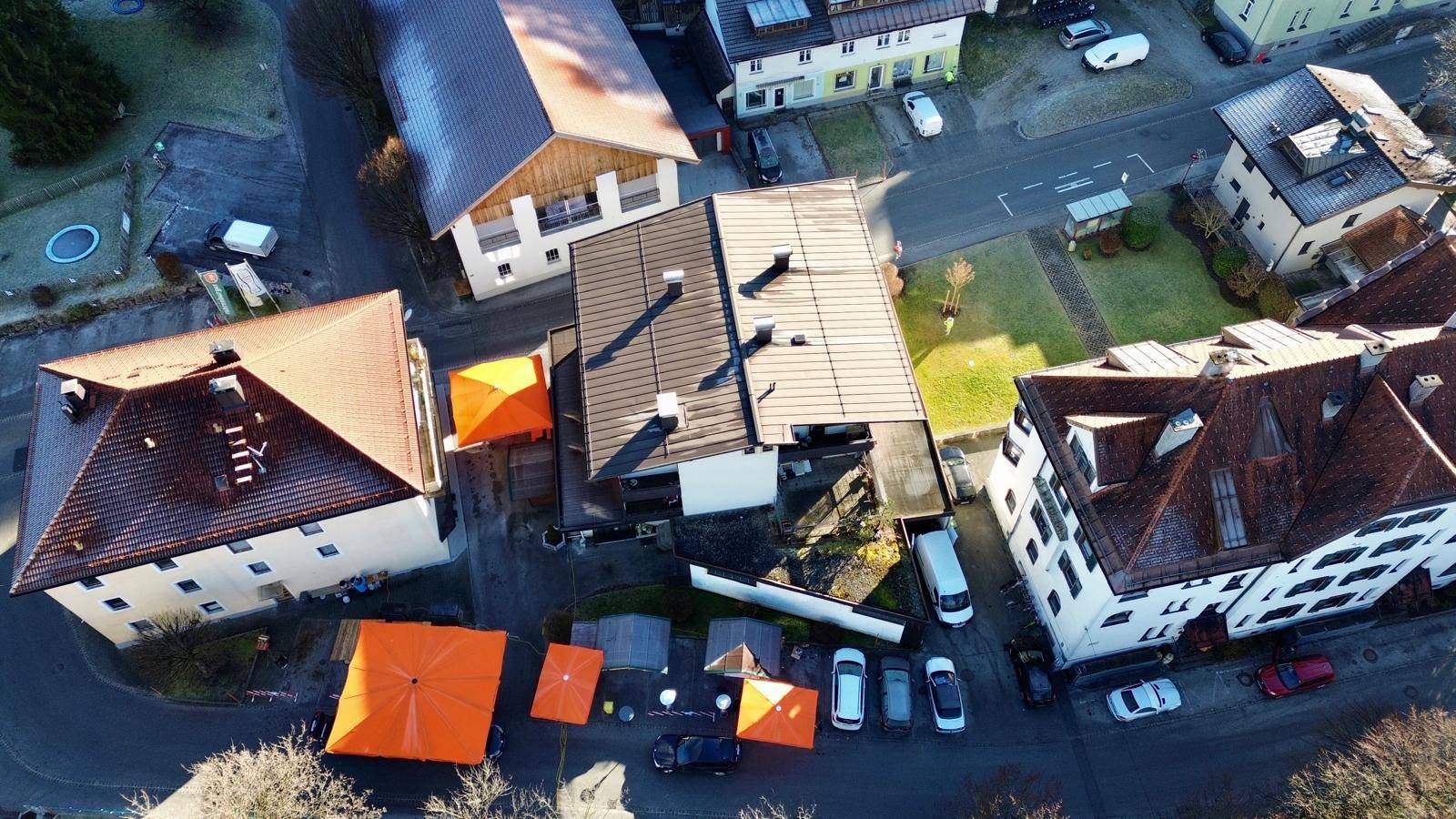 Vogelperspektive des Gebäudes und der umliegenden Nachbarschaft mit Dächern und Parkplätzen.