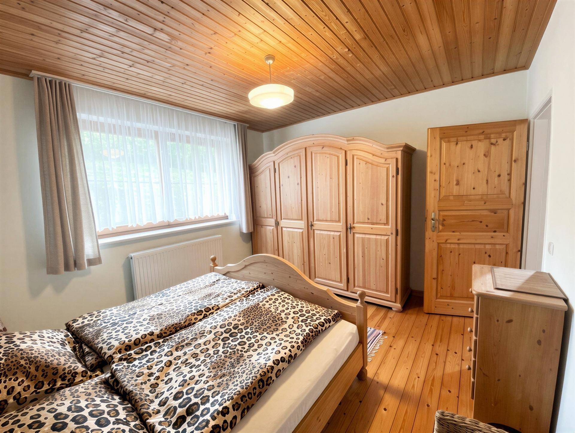 Gemütliches Schlafzimmer mit Doppelbett, Holzschrank und Holzdecke, hell und freundlich.