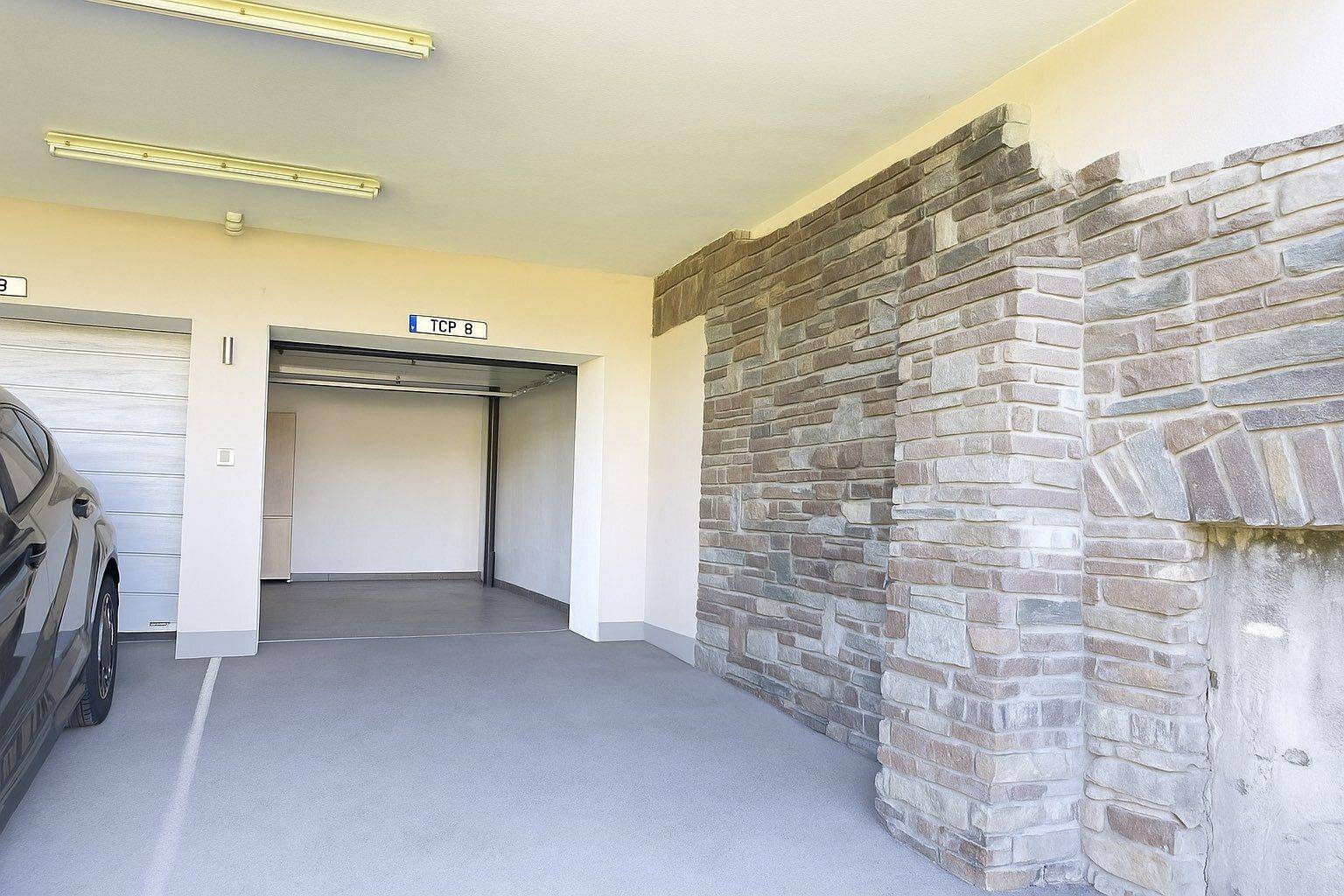 Carport mit Steinwand bzw. überdachter Stellplatz mit Garage dahinter