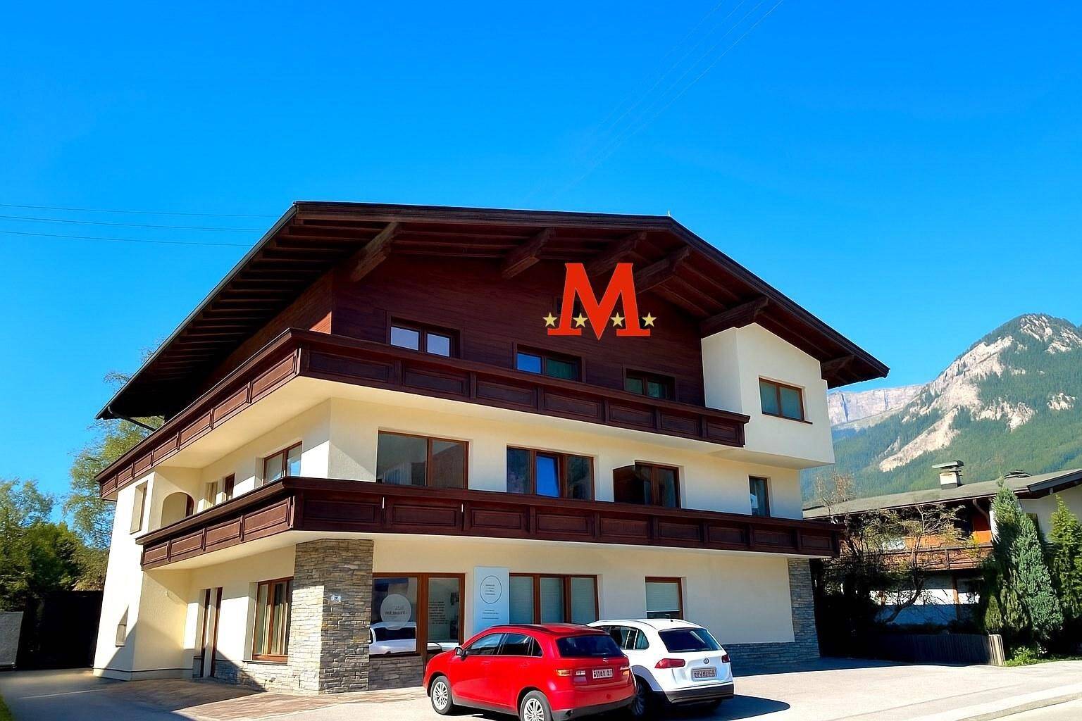Modernes Mehrfamilienhaus im alpinen Stil mit Balkonen und markantem Dachüberstand.