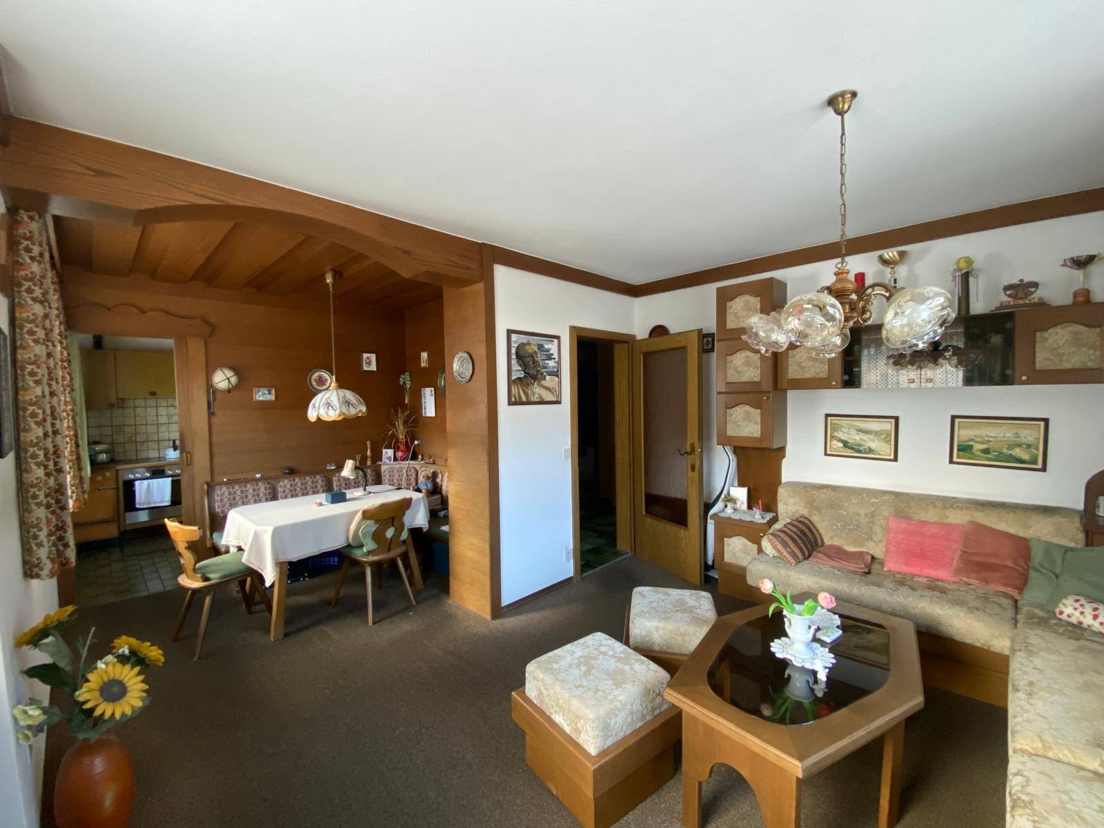 Traditioneller Wohn-Essbereich mit Holzelementen, gemütlichem Sofa und Blick zur Küche.
