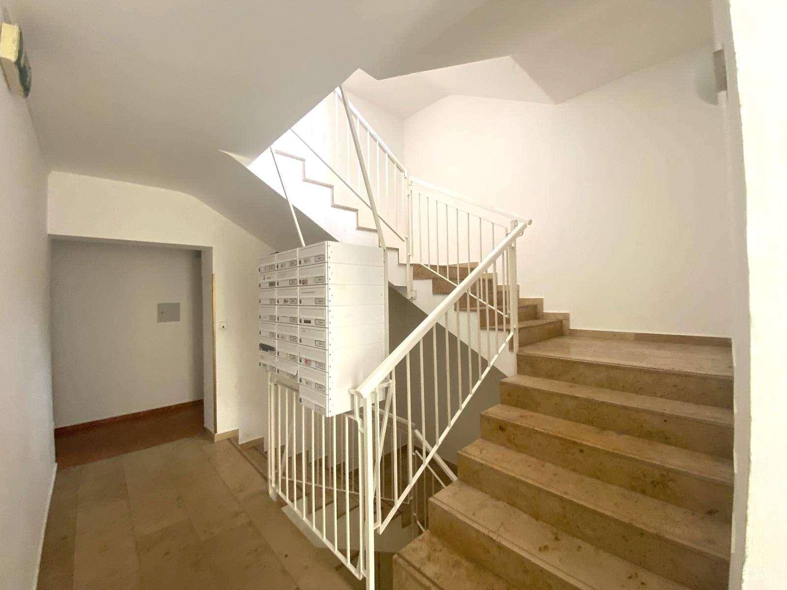 Treppenhaus mit Marmorstufen und Metallgeländer in einem Mehrfamilienhaus.