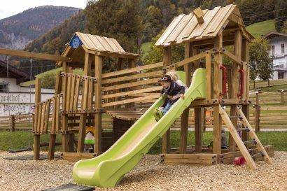 Großer Holzspielplatz mit Rutsche und Klettergerüst, ideal für Kinder zum Spielen.