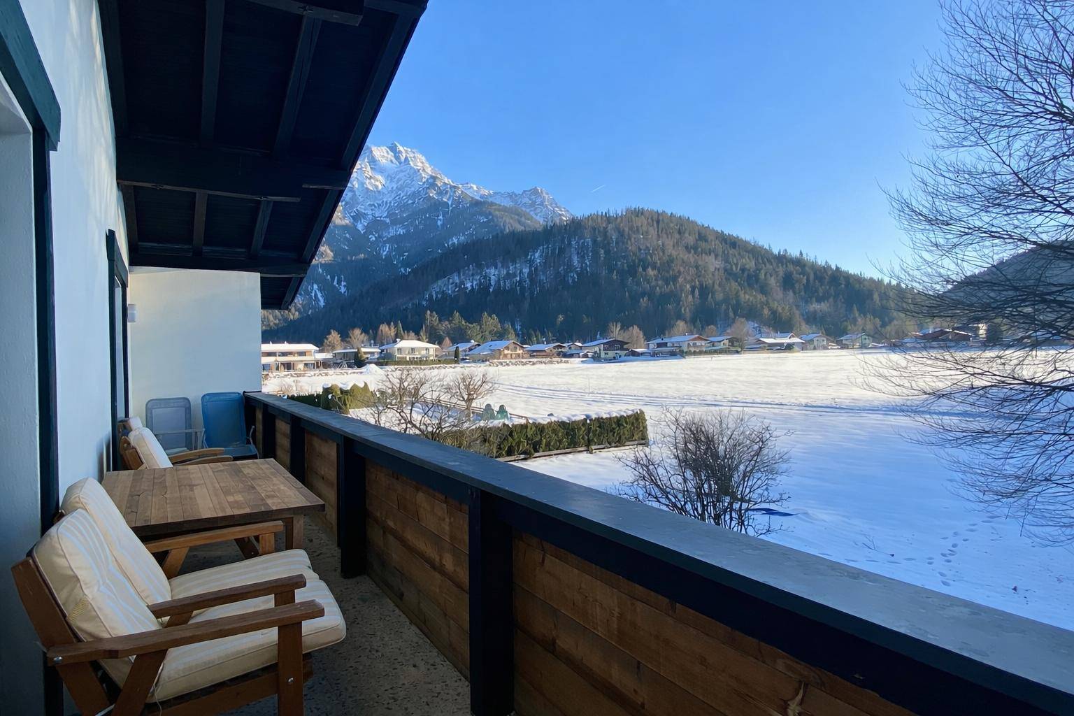 Balkon mit Sitzgelegenheiten und weitem Blick auf die schneebedeckten Berge und das Tal.