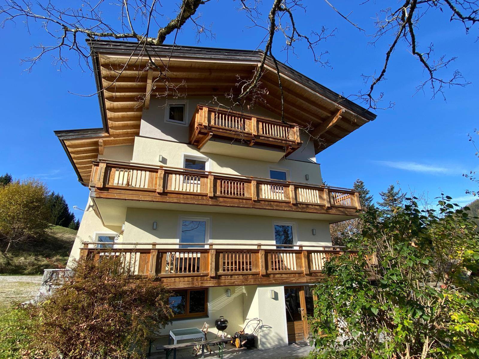 Seitenansicht des Hauses mit mehreren Holzbalconen und traditioneller Architektur in sonniger Lage.