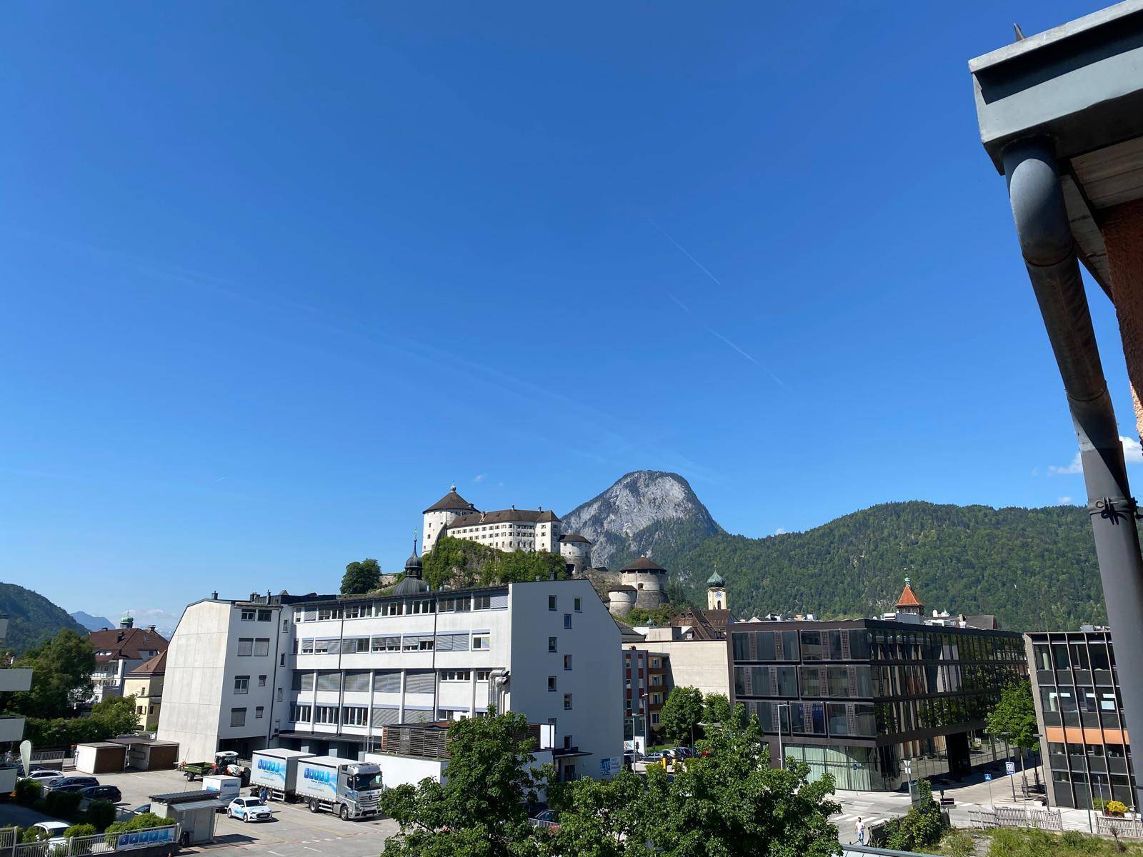 Weitläufiger Blick über die Stadt mit Gebäuden, einem imposanten Berg und einer historischen Burg.