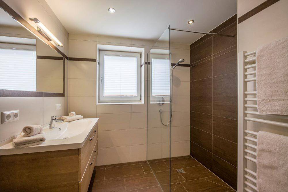Modernes Badezimmer mit begehbarer Dusche, Waschtisch und beheiztem Handtuchhalter.