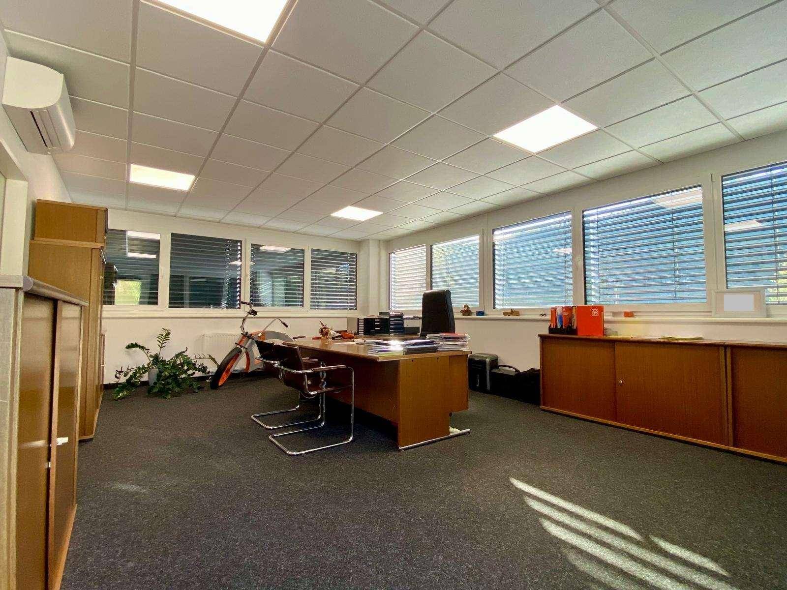 Geräumiges Chefbüro mit großem Holzschreibtisch, bequemen Stühlen und Klimaanlage, bietet eine professionelle Umgebung.