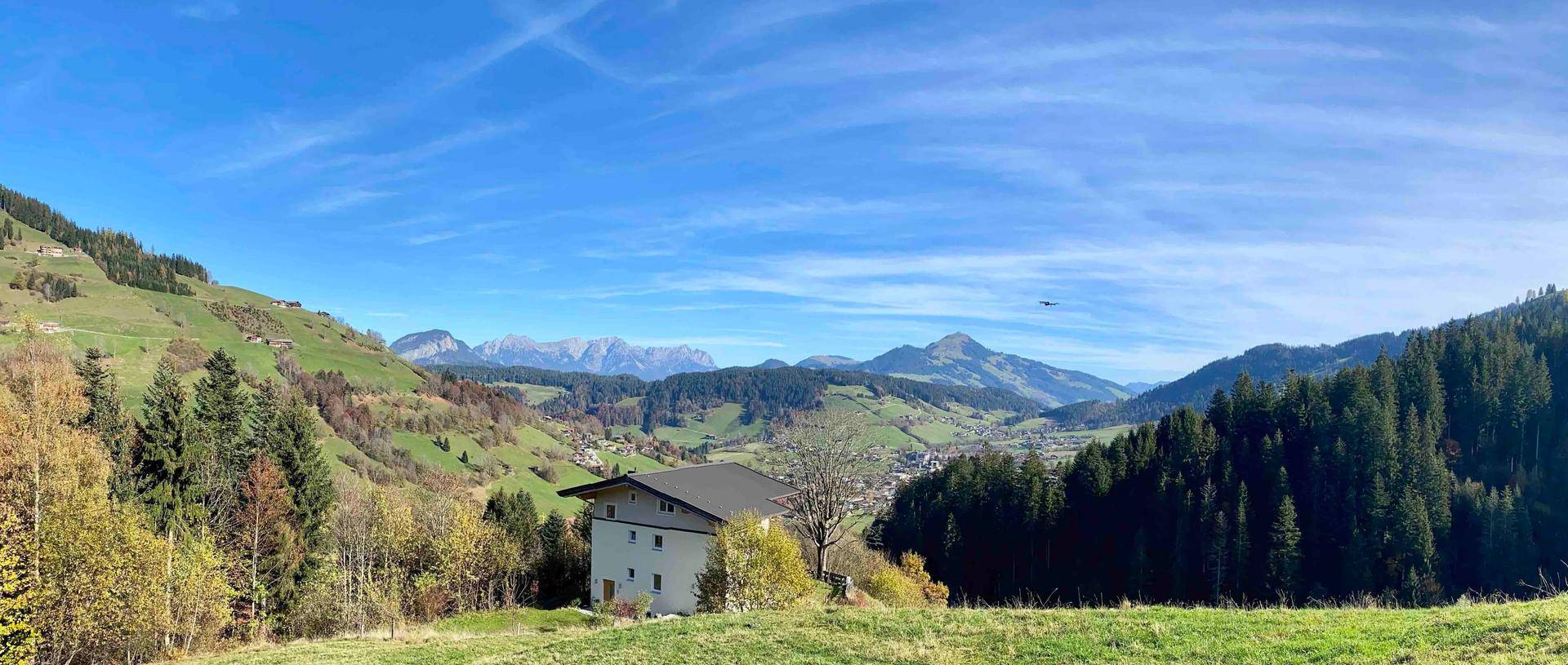 Weitläufige Panoramaansicht des Hauses in einer hügeligen Landschaft mit Bergen im Hintergrund.