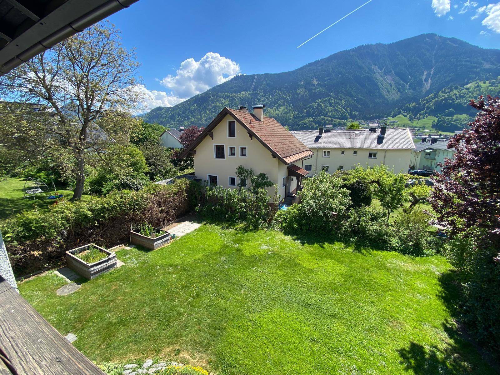 Großer Garten mit Rasenfläche, Hochbeeten und Blick auf ein charmantes Haus.