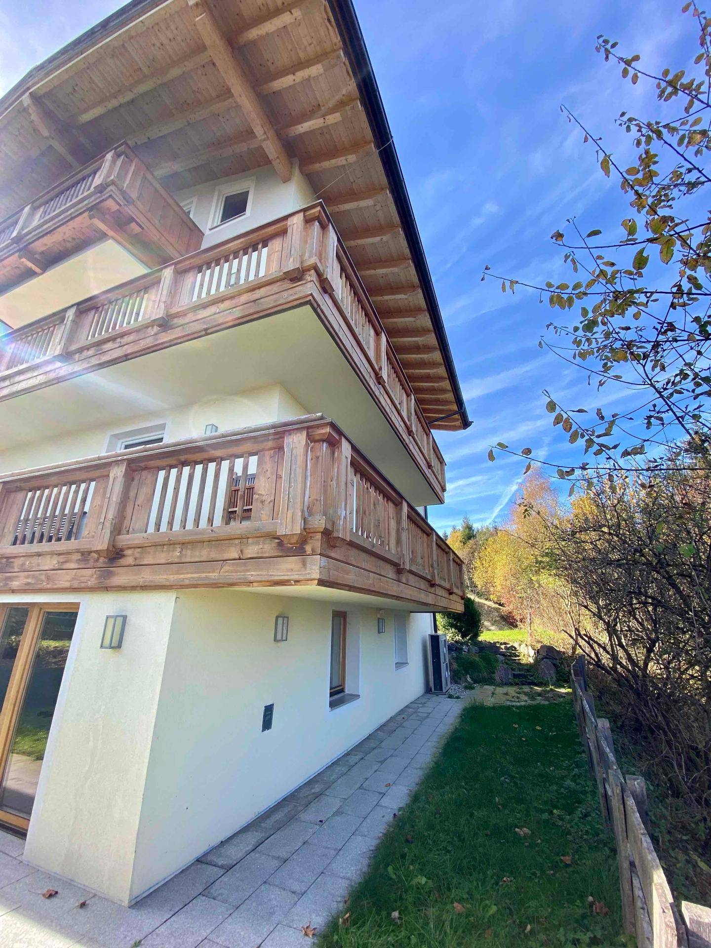 Seitenansicht des Hauses mit mehreren Holzbalconen und traditioneller Architektur in sonniger Lage.