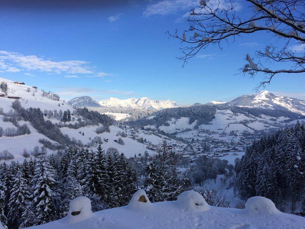 Weitläufiger Winterblick auf die verschneite Berglandschaft und das darunterliegende Tal.