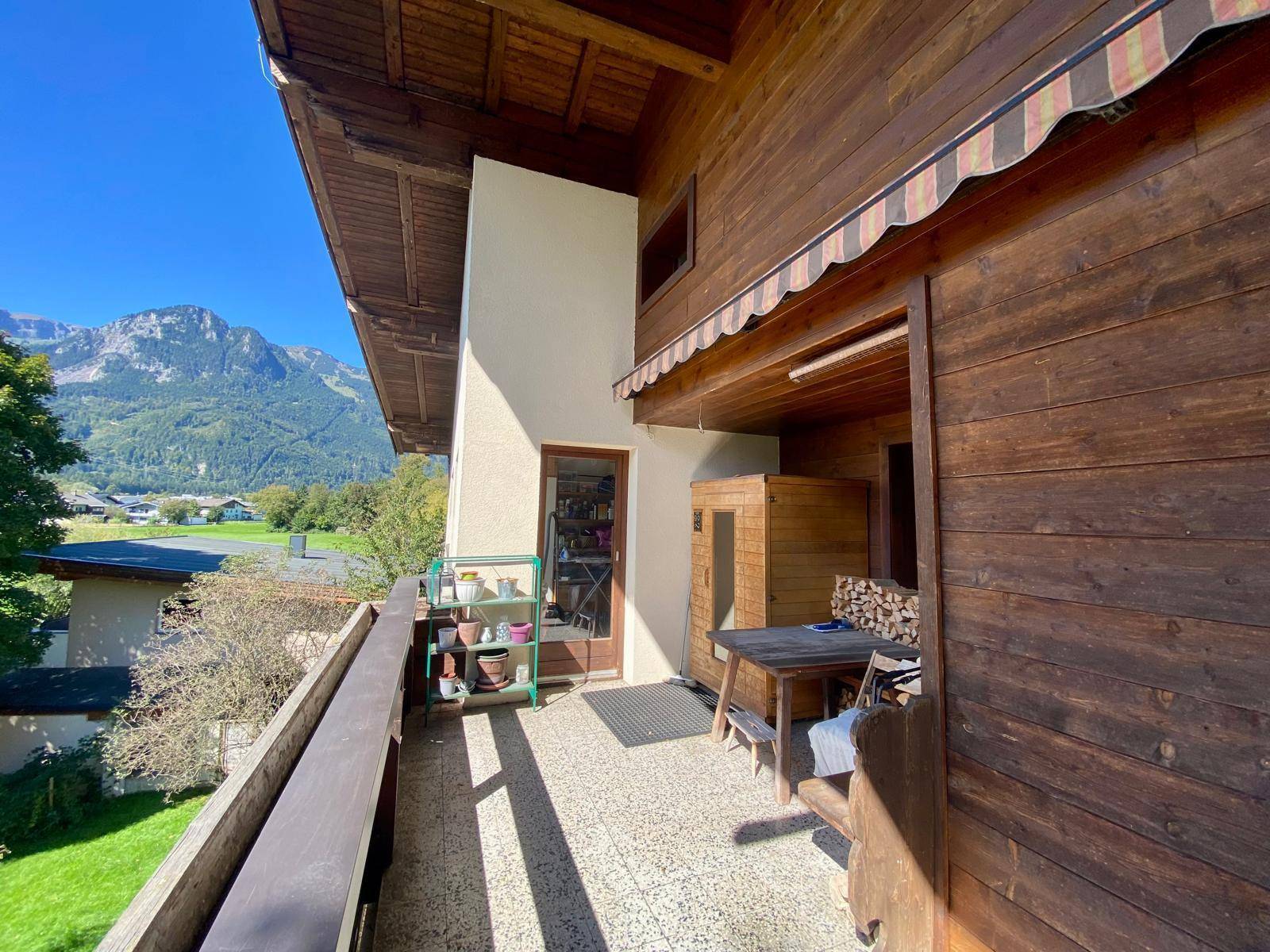 Geräumiger Balkon mit Holzboden, Sitzgelegenheiten und Blick auf die umliegende Natur.