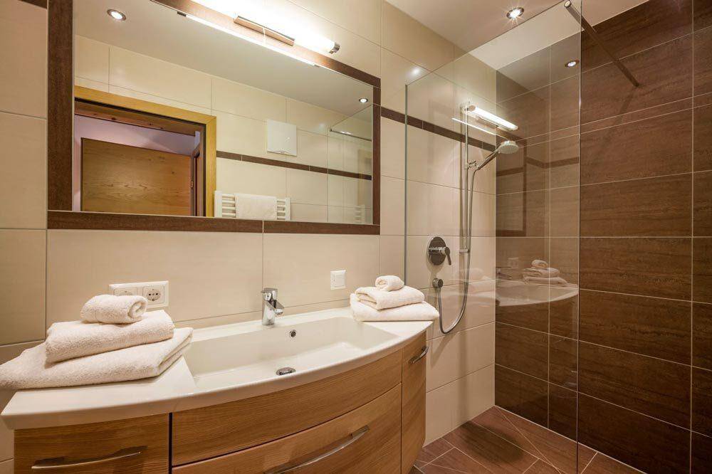 Modernes Badezimmer mit begehbarer Dusche, Waschtisch und großem Spiegel.