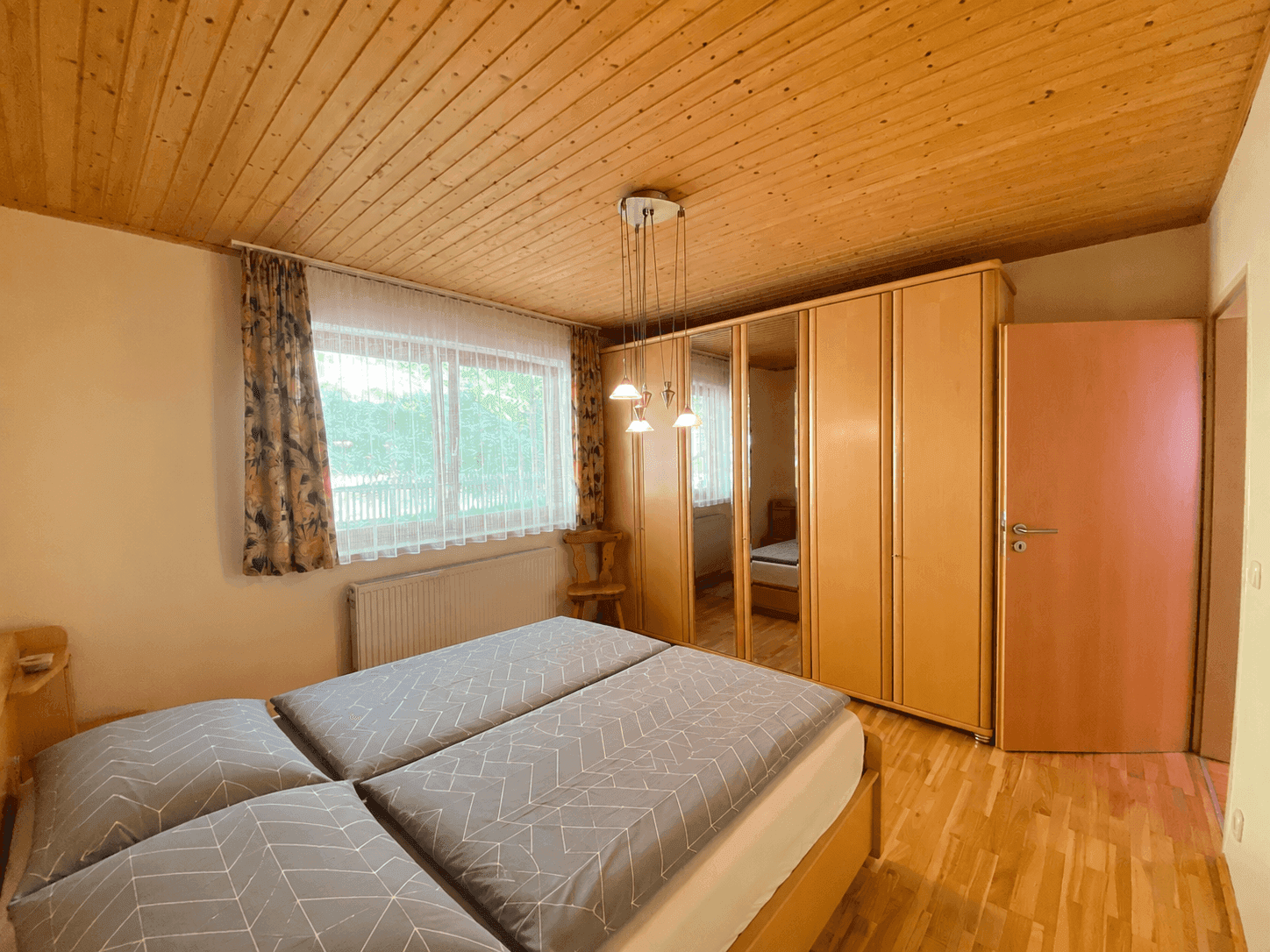 Geräumiges Schlafzimmer mit Doppelbett, großem Kleiderschrank und Holzdecke.