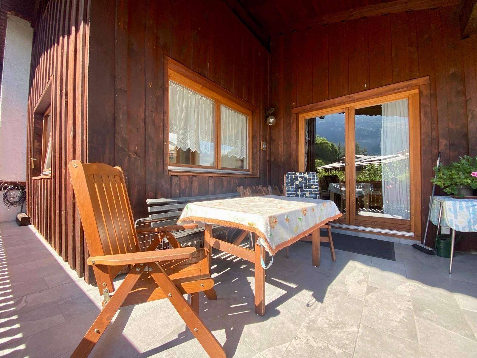 Überdachter Balkon mit Holztisch und Stühlen, ideal für entspannte Stunden im Freien.