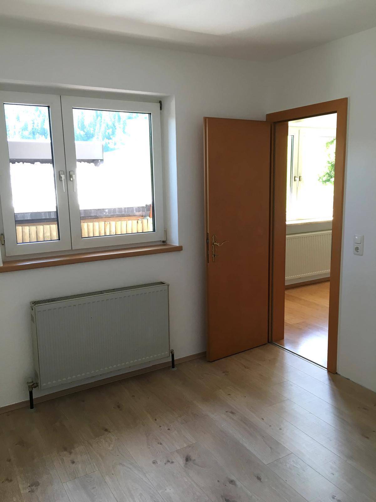 Helles Zimmer mit Fenster, Heizkörper und neuem Holzboden, ideal als Schlaf- oder Arbeitszimmer.