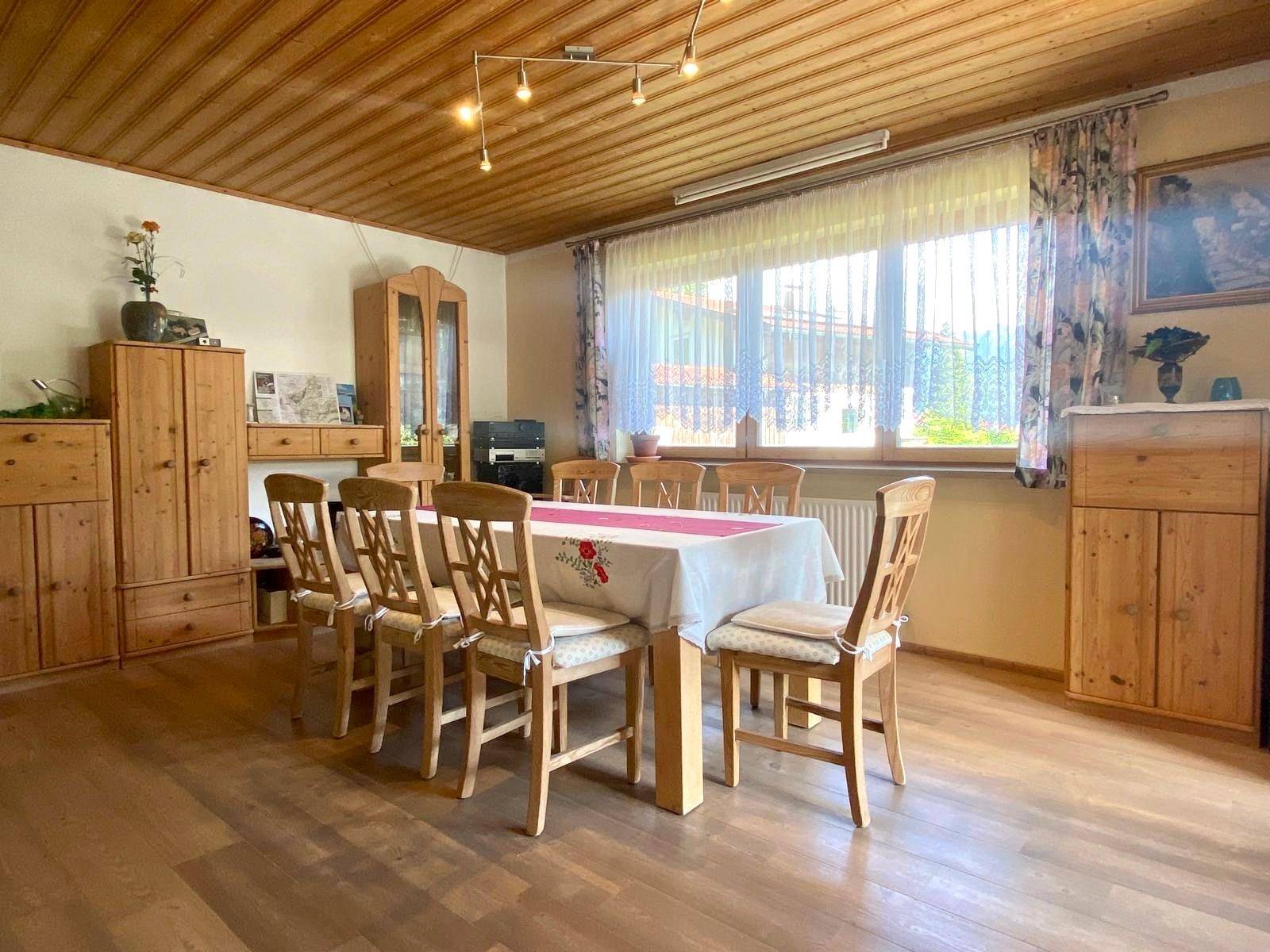 Gemütlicher Essbereich mit Holztisch und Stühlen, umgeben von traditionellen Holzmöbeln und Deckenverkleidung.