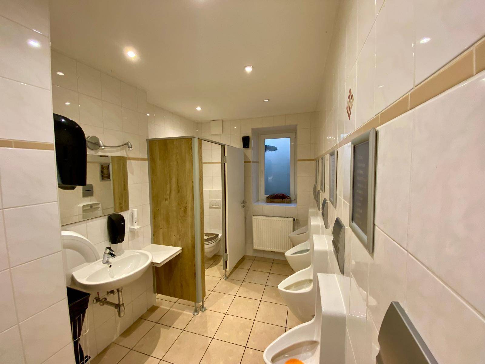 Saubere und funktionale öffentliche Toiletten mit mehreren Urinalen und Waschbecken.