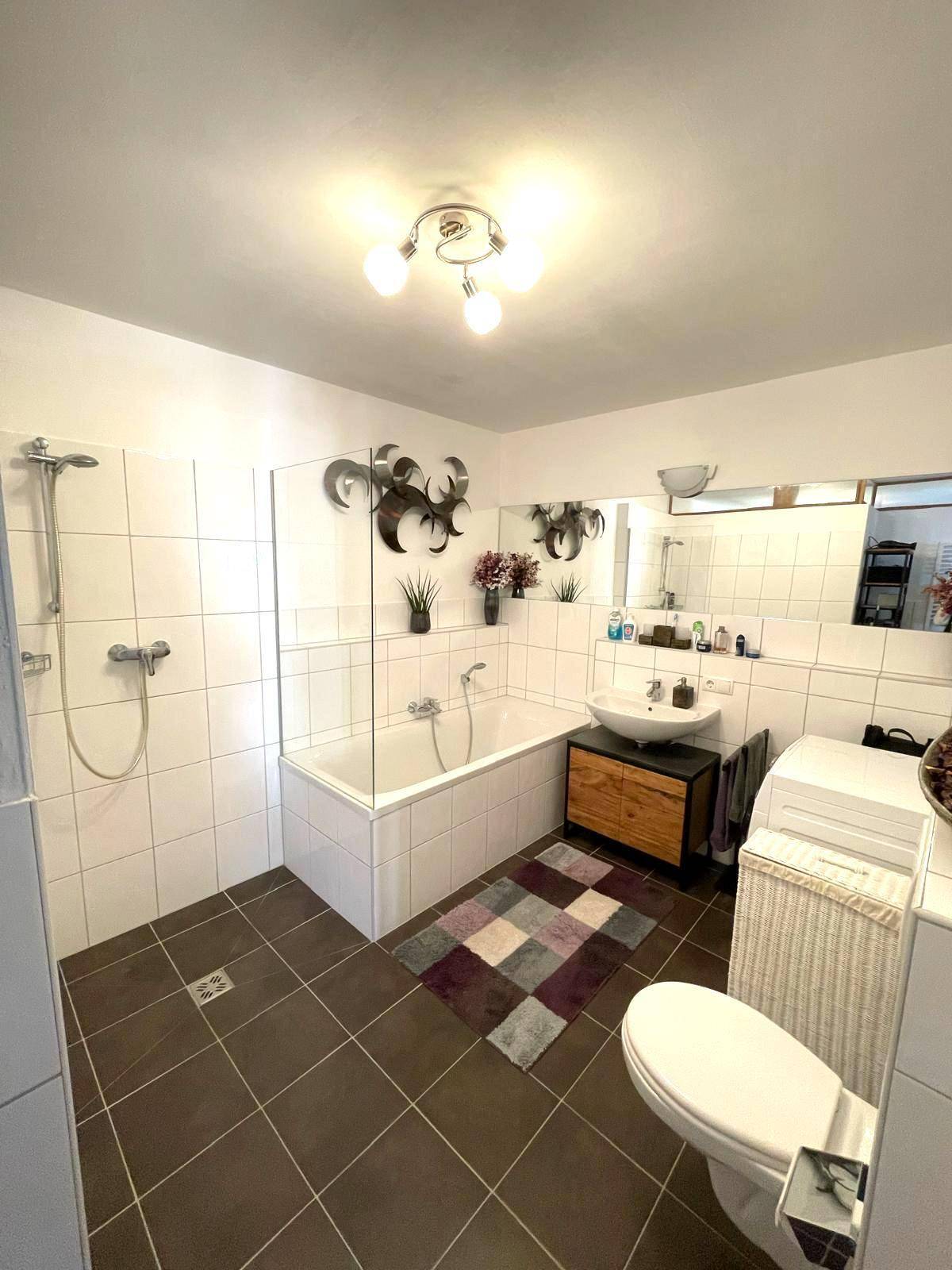 Modernes Badezimmer mit Badewanne, Dusche und großformatigen Fliesen.