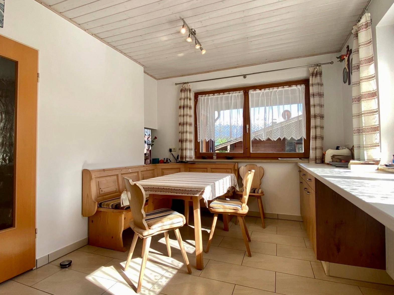 Helle Wohnküche mit Einbauküche, Essbereich und Fenster mit Blick ins Grüne.