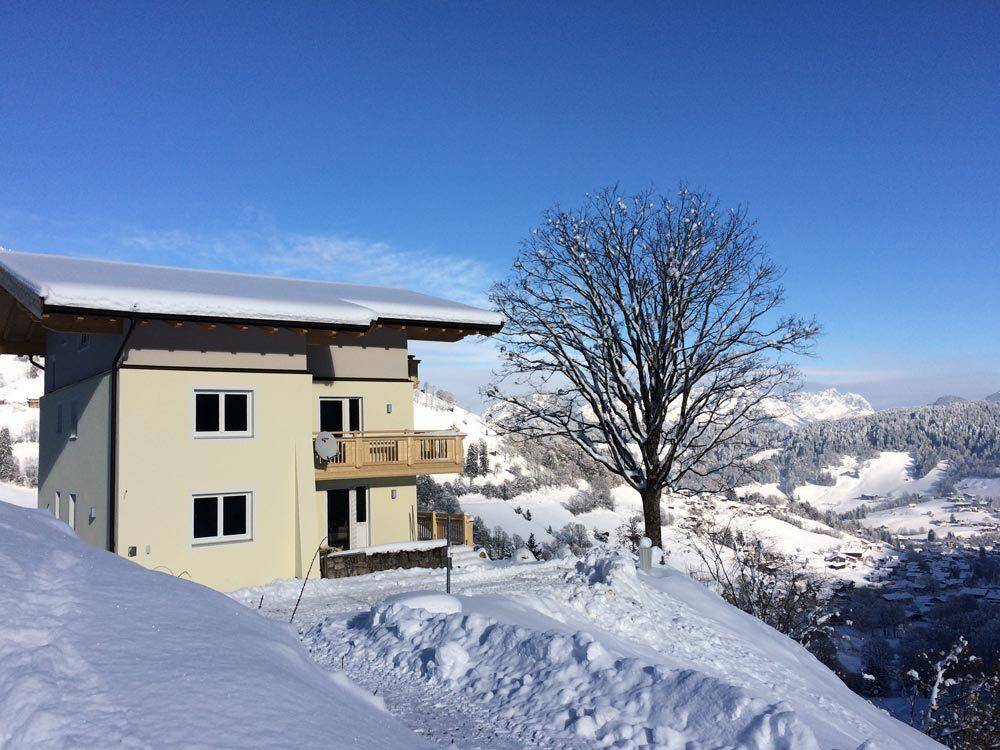 Das Haus in einer idyllischen Winterlandschaft, umgeben von Schnee und mit Bergblick.