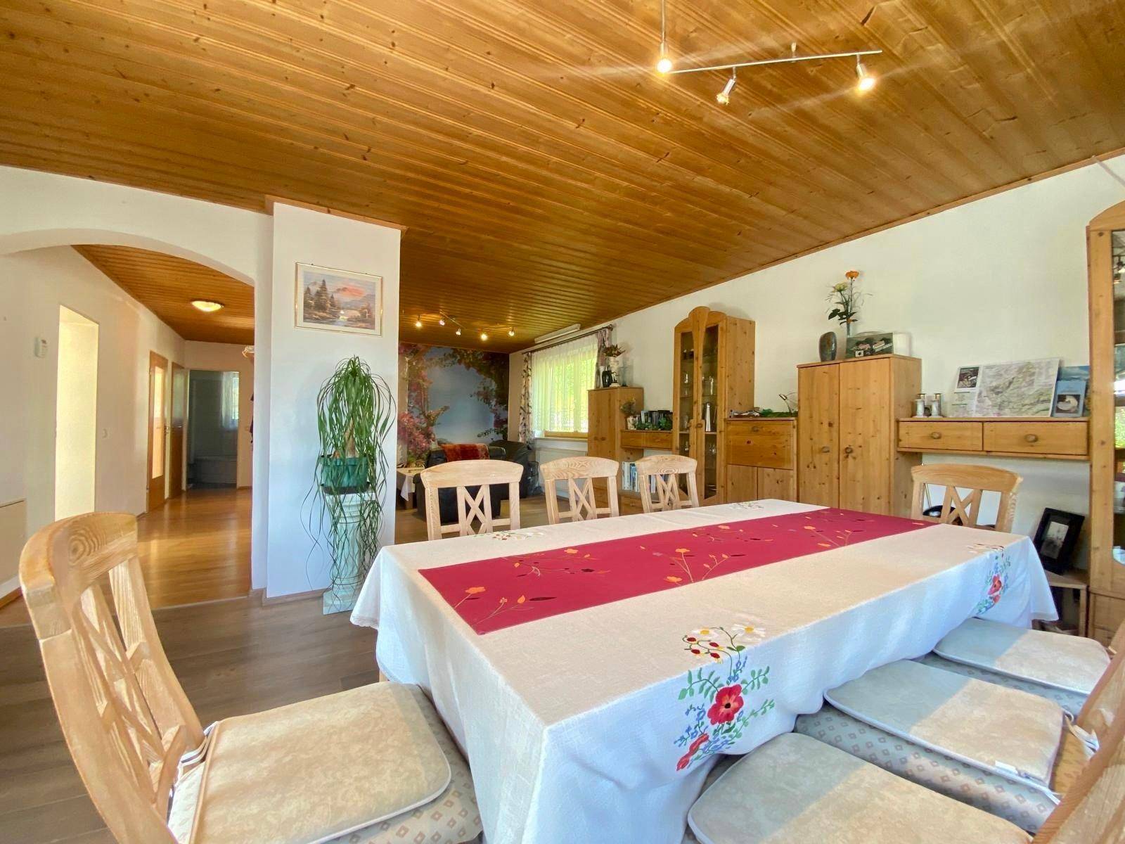 Offener Wohn- und Essbereich mit Holztisch, traditionellen Möbeln und einer dekorativen Wandtapete.