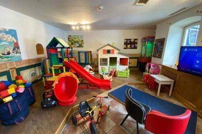 Farbenfrohes Spielzimmer mit verschiedenen Spielgeräten, Rutsche und Spielhäusern für Kinder.