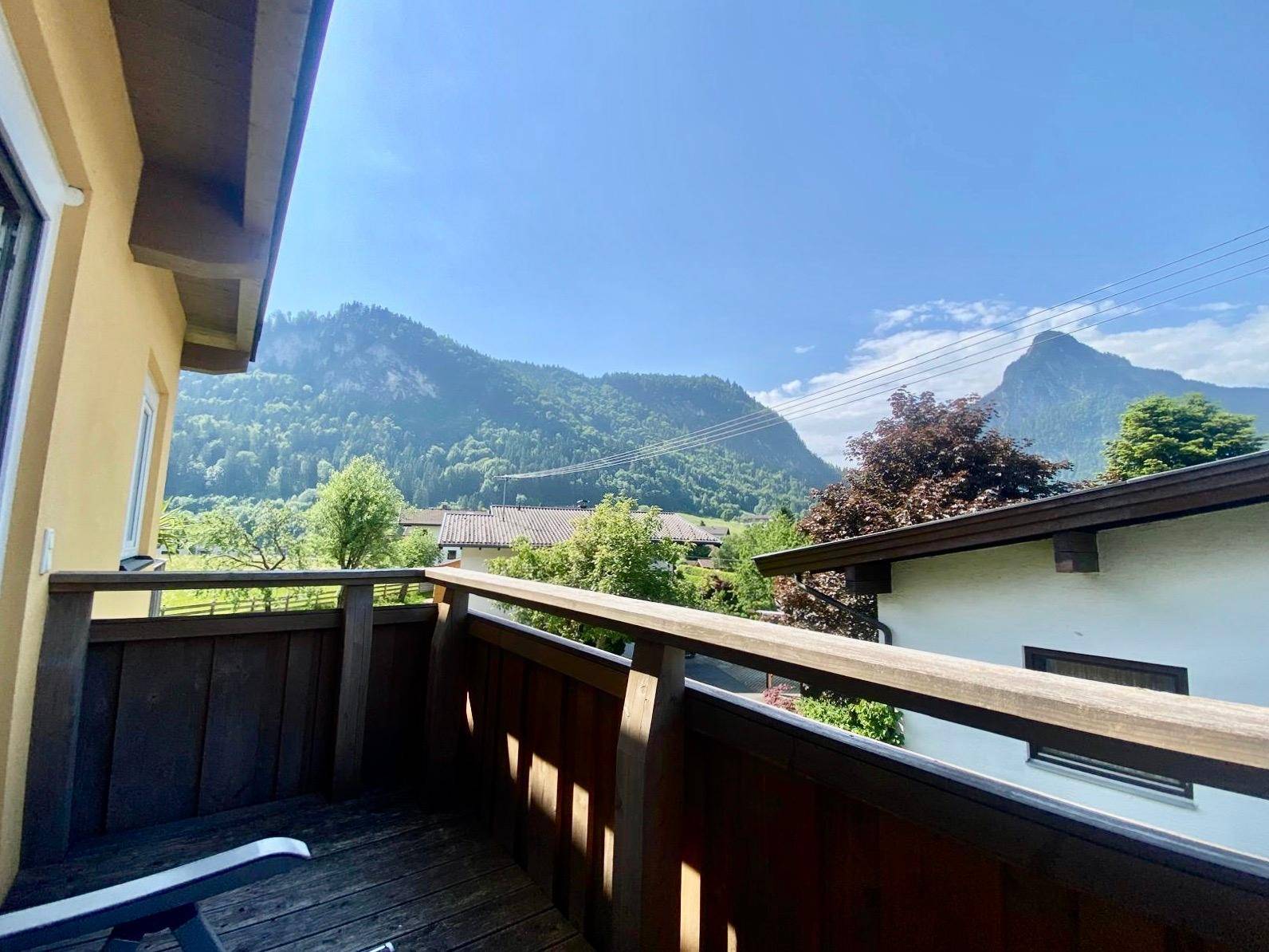 Holzbalkon mit Bergblick und grüner Umgebung, ideal zum Entspannen im Freien.
