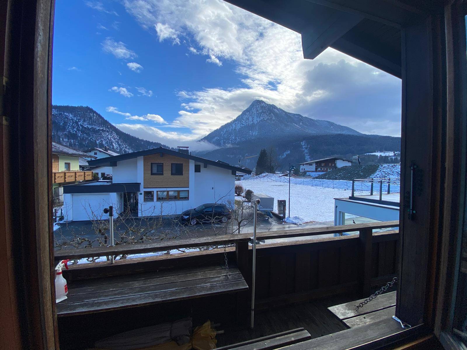 Blick vom Balkon auf die verschneite Berglandschaft unter blauem Himmel.