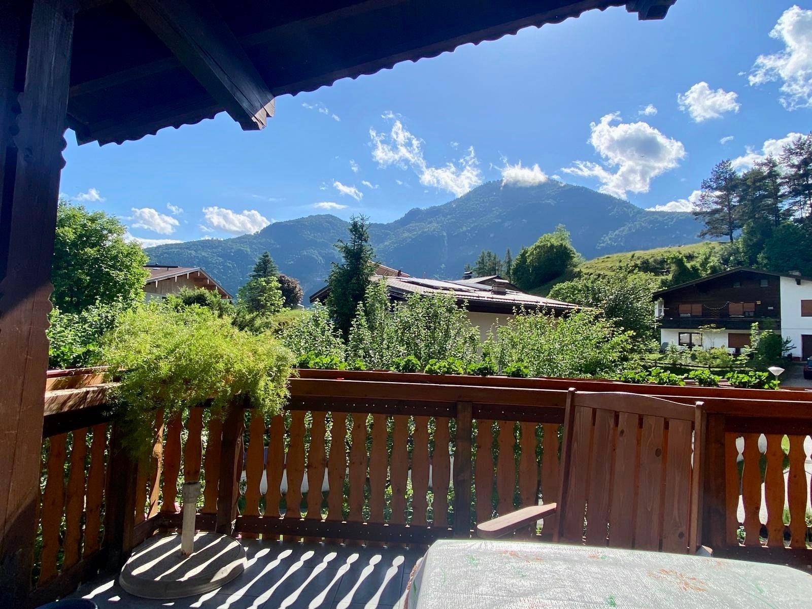 Geräumiger Balkon mit Holzgeländer und weitem Blick auf die umliegende Bergwelt.