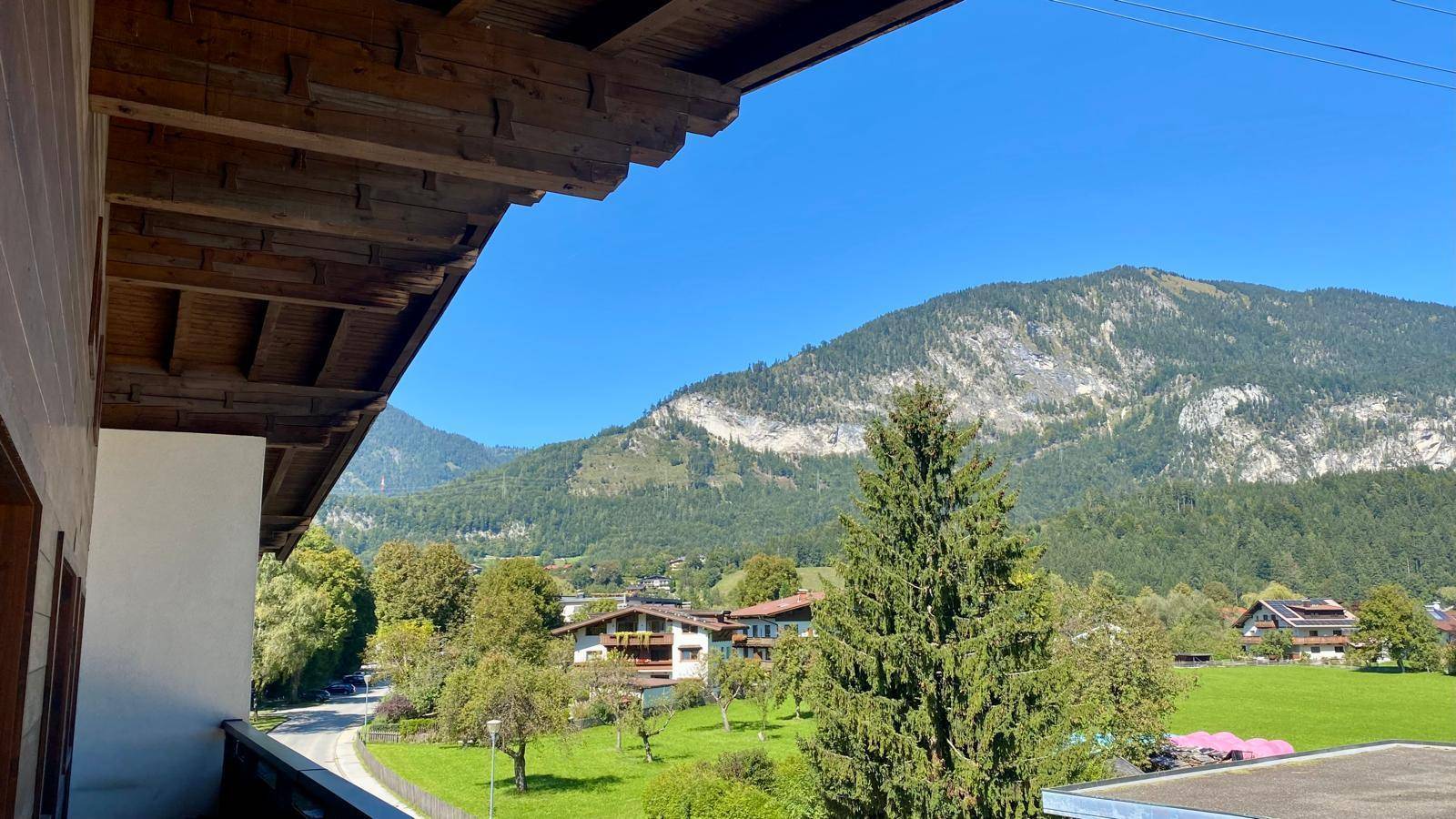 Panoramablick vom Balkon auf die umliegende Berglandschaft und grüne Wiesen.