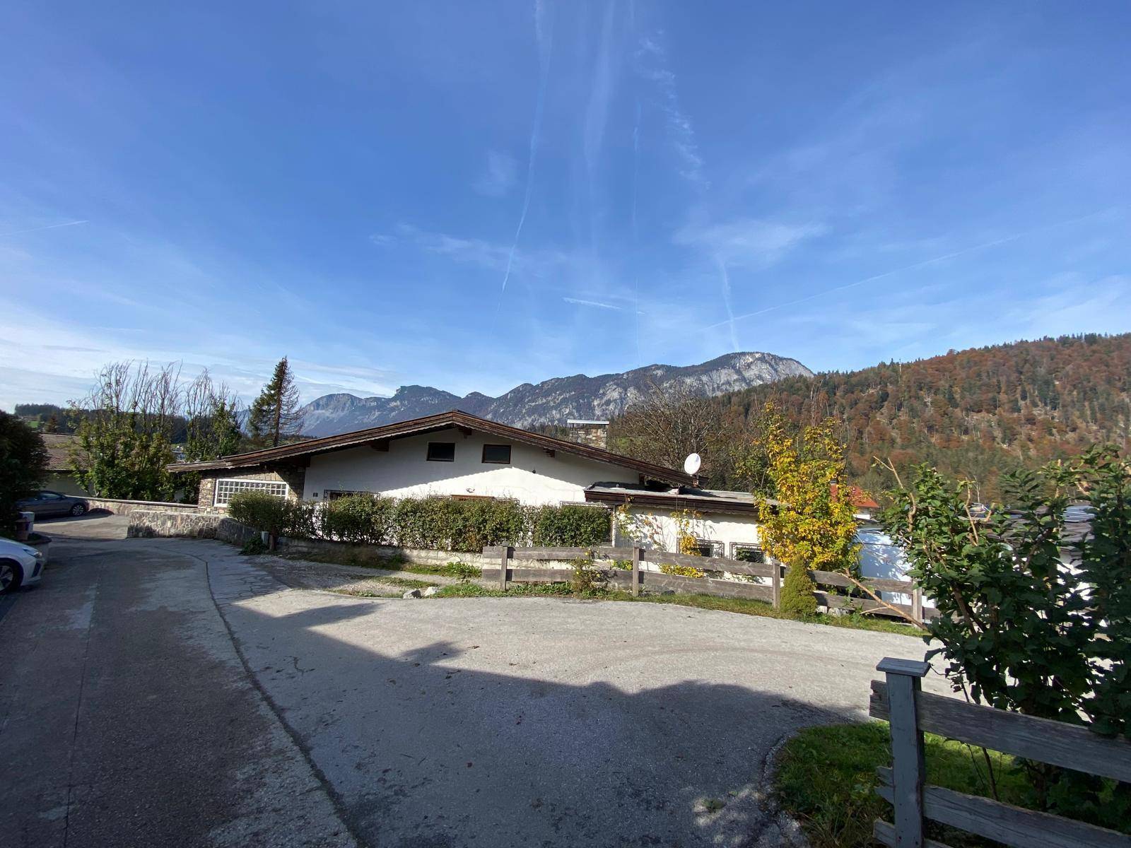 Weitläufige Ansicht des Hauses mit Zufahrt und Garten, umgeben von Bergen und Natur.