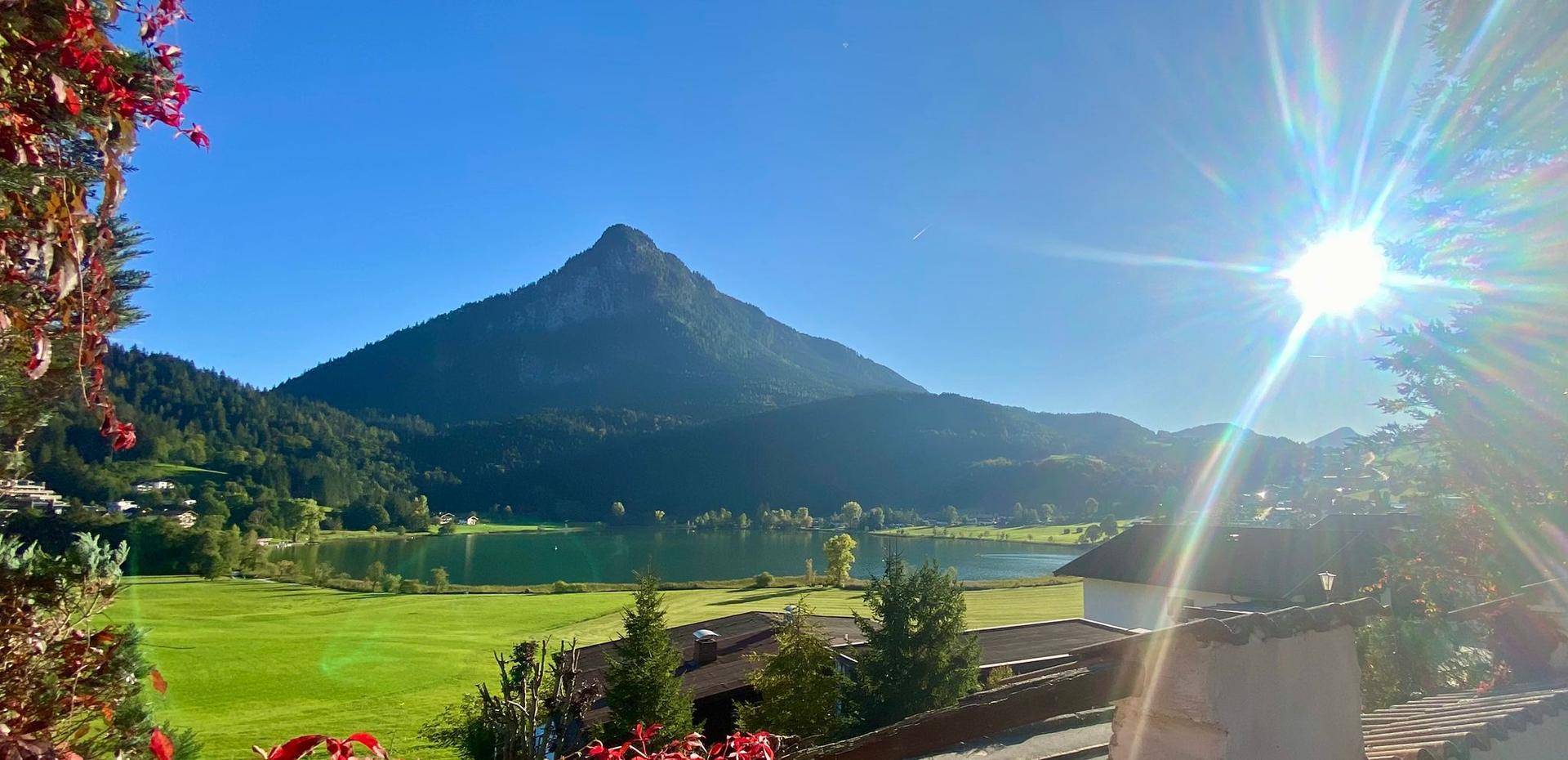 Atemberaubender Blick auf einen See und Berge unter einem sonnigen blauen Himmel.