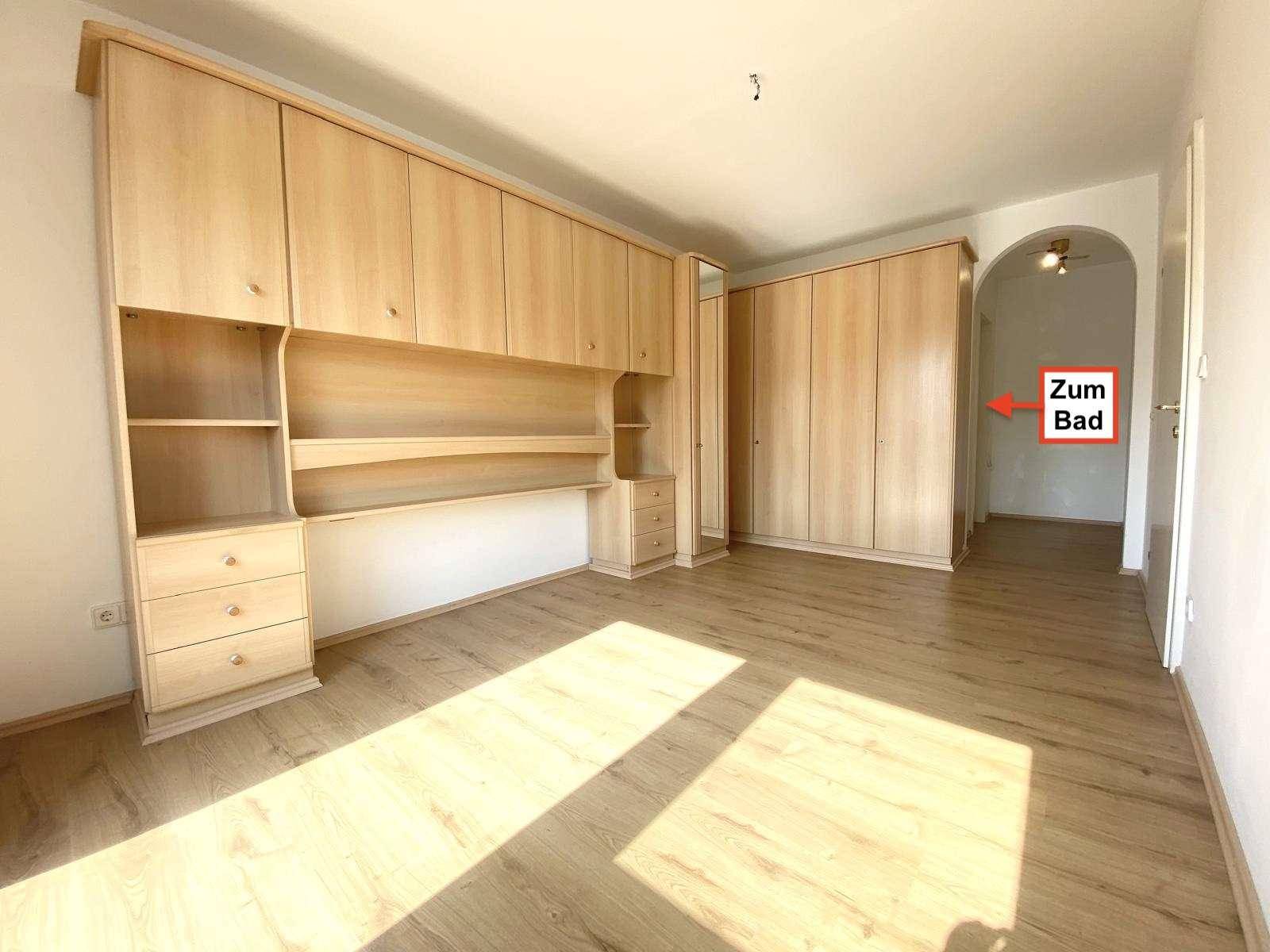 Geräumiges Schlafzimmer mit Einbauschränken, Laminatboden und direktem Zugang zum Badezimmer.