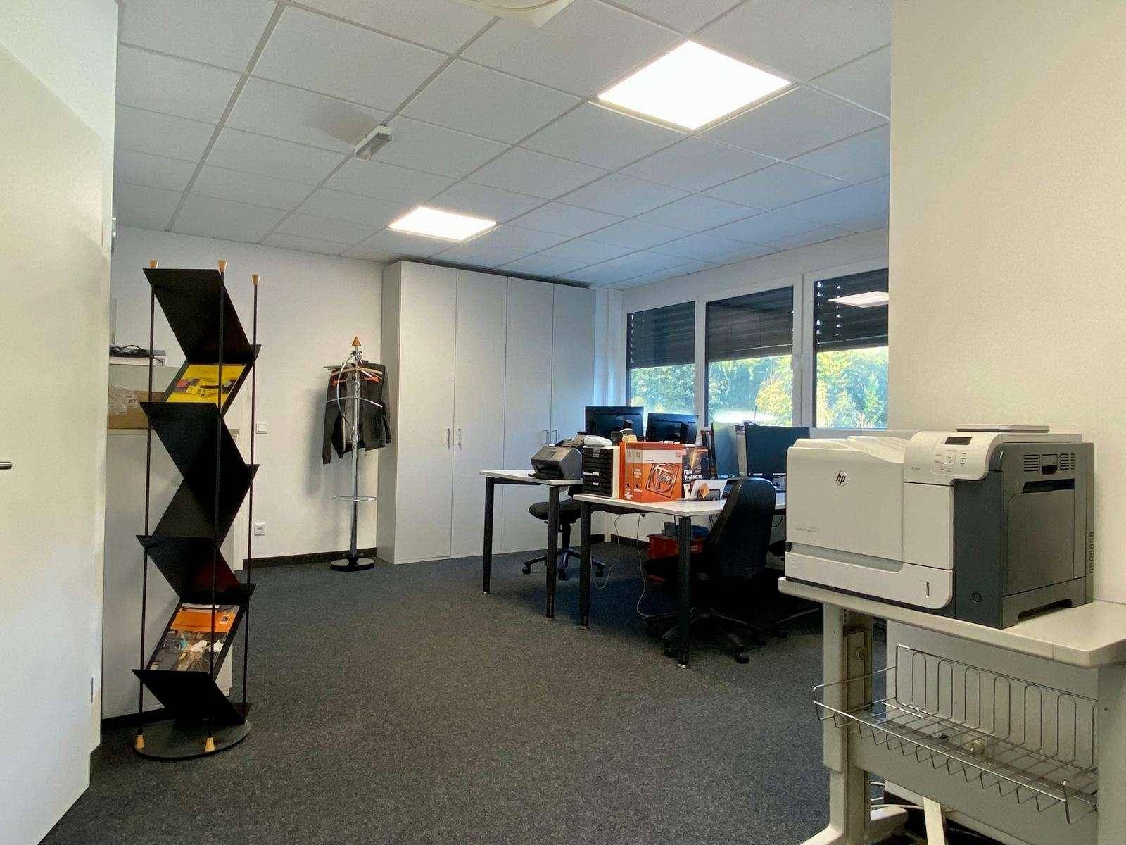Großzügiger Bürobereich mit mehreren Arbeitsplätzen, Computern und einem Drucker, ideal für Teamarbeit.