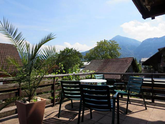 Sonniger Balkon mit Gartenmöbeln, Palmen und einem schönen Blick auf die Berge.
