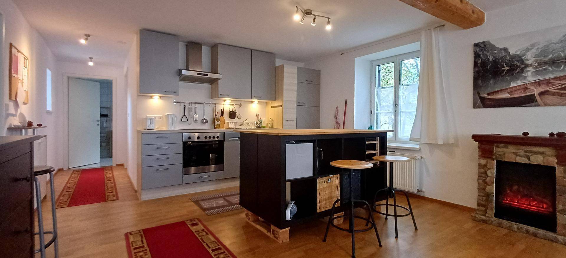 Offene Küche mit moderner Ausstattung, Kücheninsel und Kamin im angrenzenden Wohnbereich.