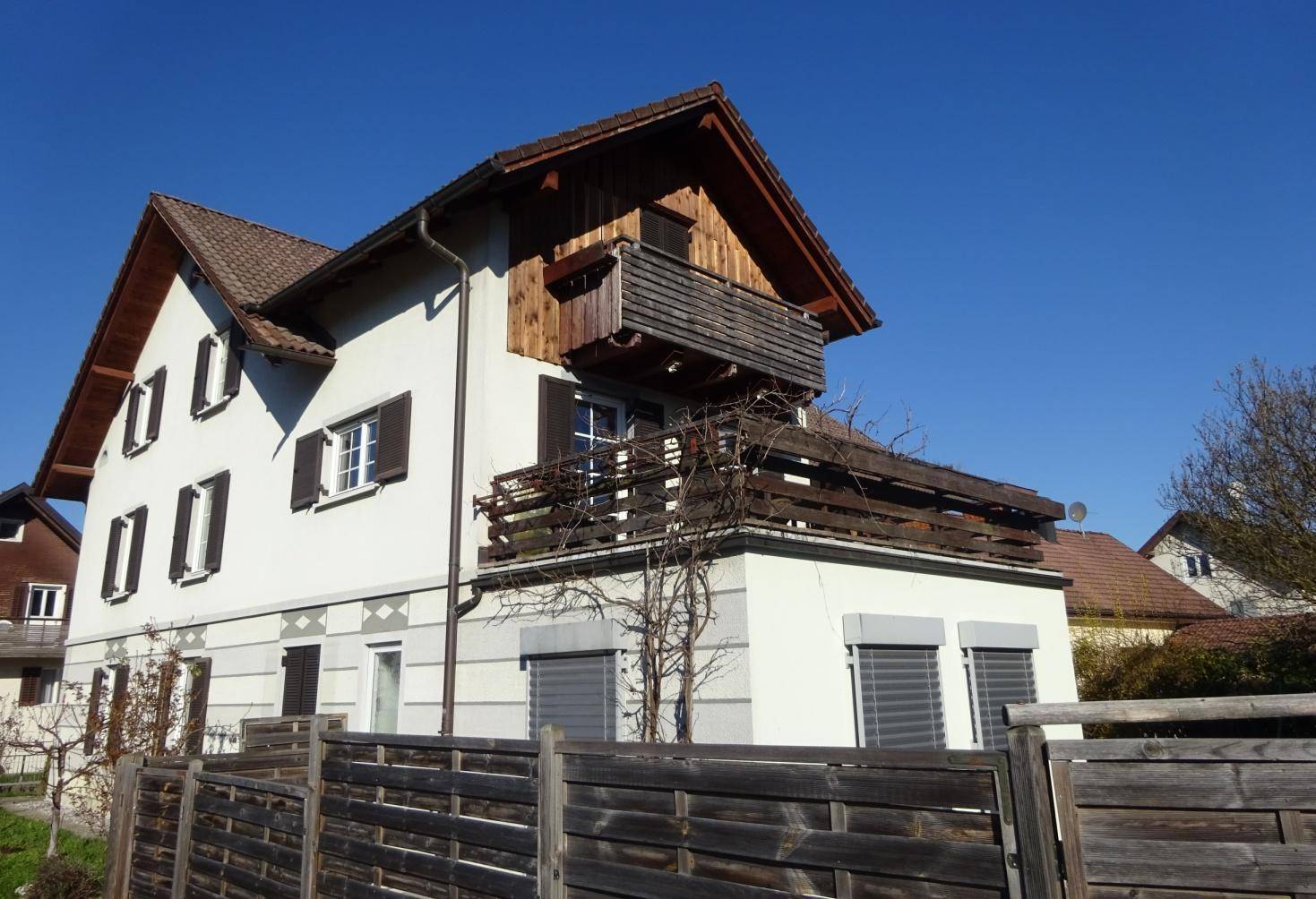 Charmantes Haus mit weißer Fassade, braunem Dach und traditionellen Holzbalkonen.