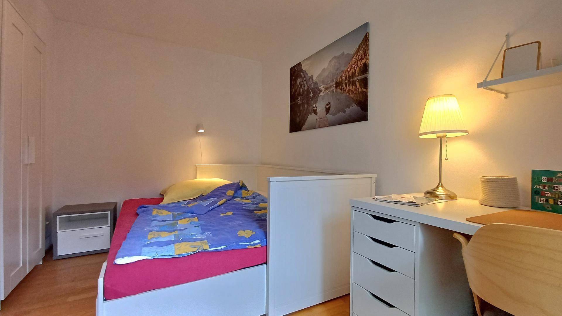 Gemütliches Schlafzimmer mit Bett, Nachttisch und integrierten Kleiderschränken.