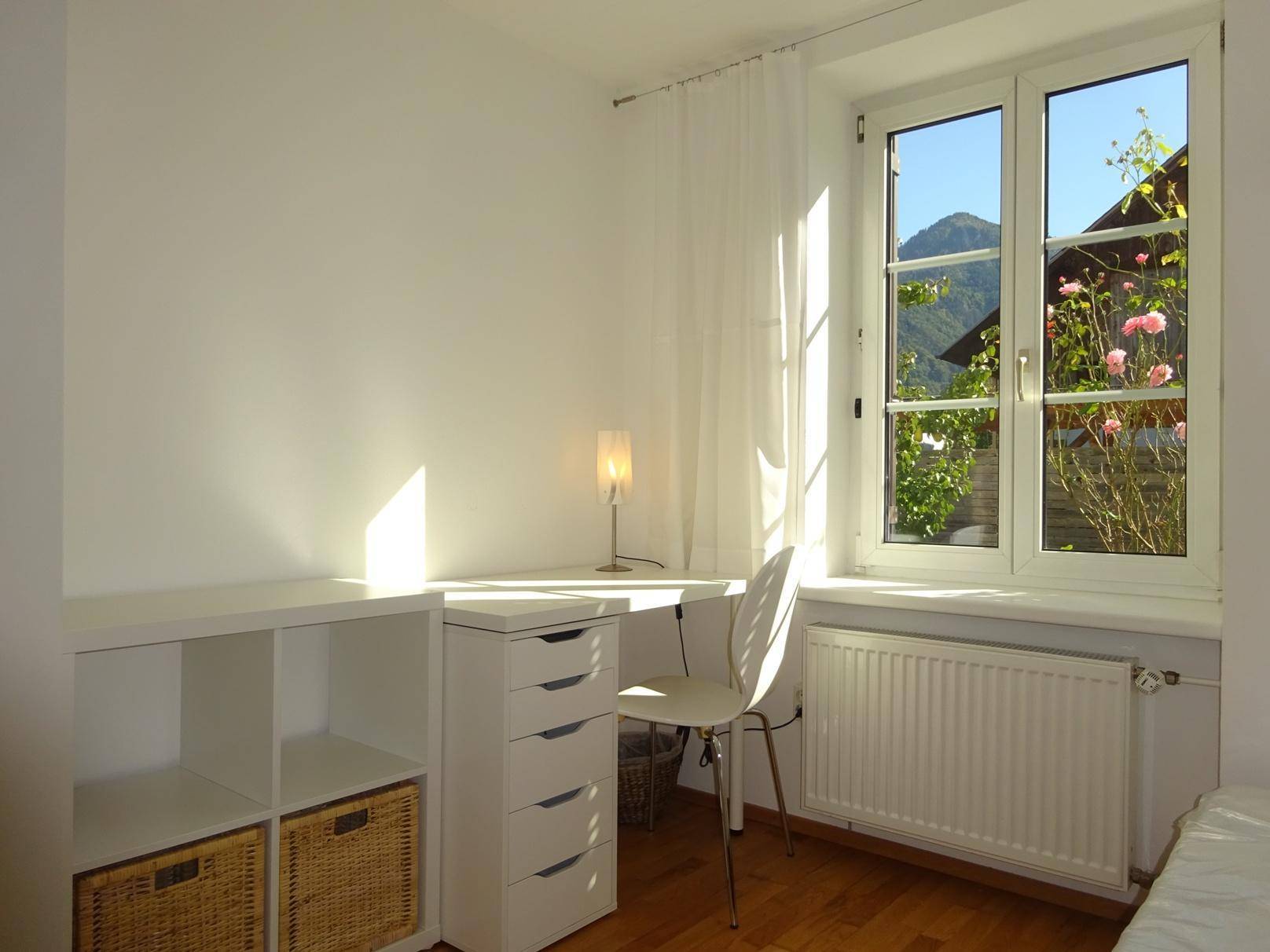 Heller Arbeitsplatz am Fenster mit Bergblick und natürlichem Lichteinfall.