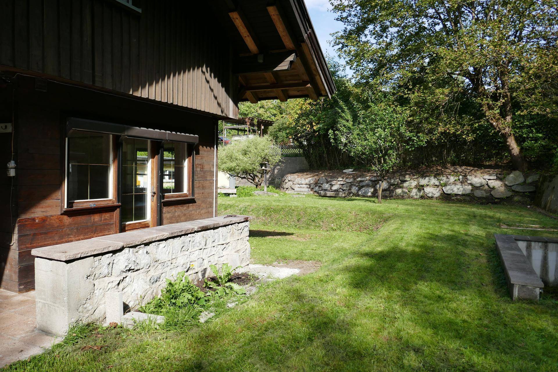 Gepflegter Gartenbereich mit Rasenfläche und Steinmauer, ideal zum Entspannen.