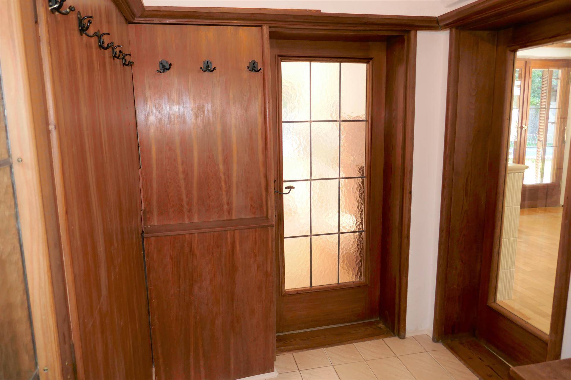 Eingangsbereich mit Garderobe und Holztür, die zu den Wohnräumen führt.