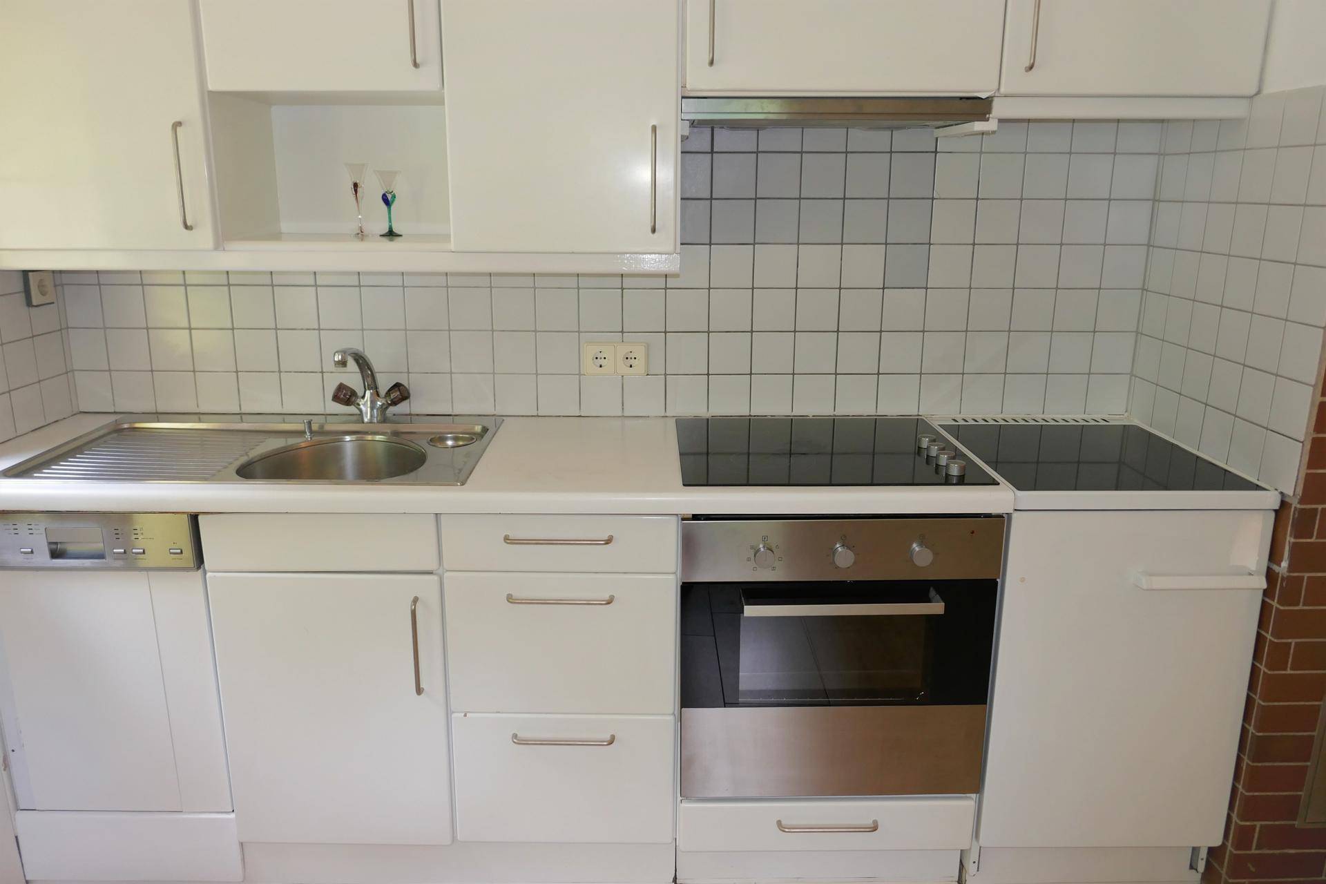 Helle Küche mit Spüle, Kochfeld und Backofen, ideal für den täglichen Gebrauch.