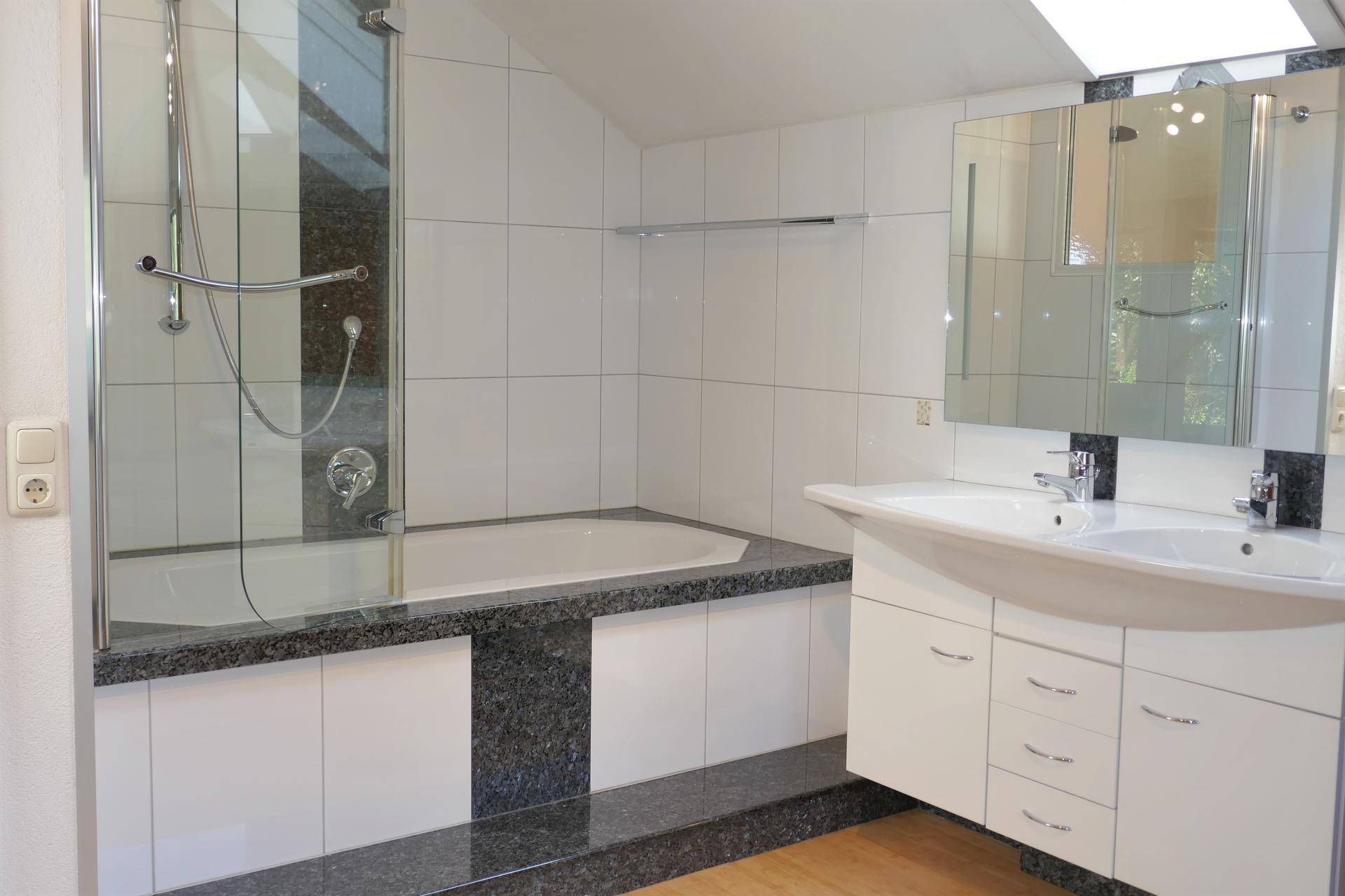 Modernes Badezimmer mit Doppelwaschbecken, Badewanne und Duschabtrennung.
